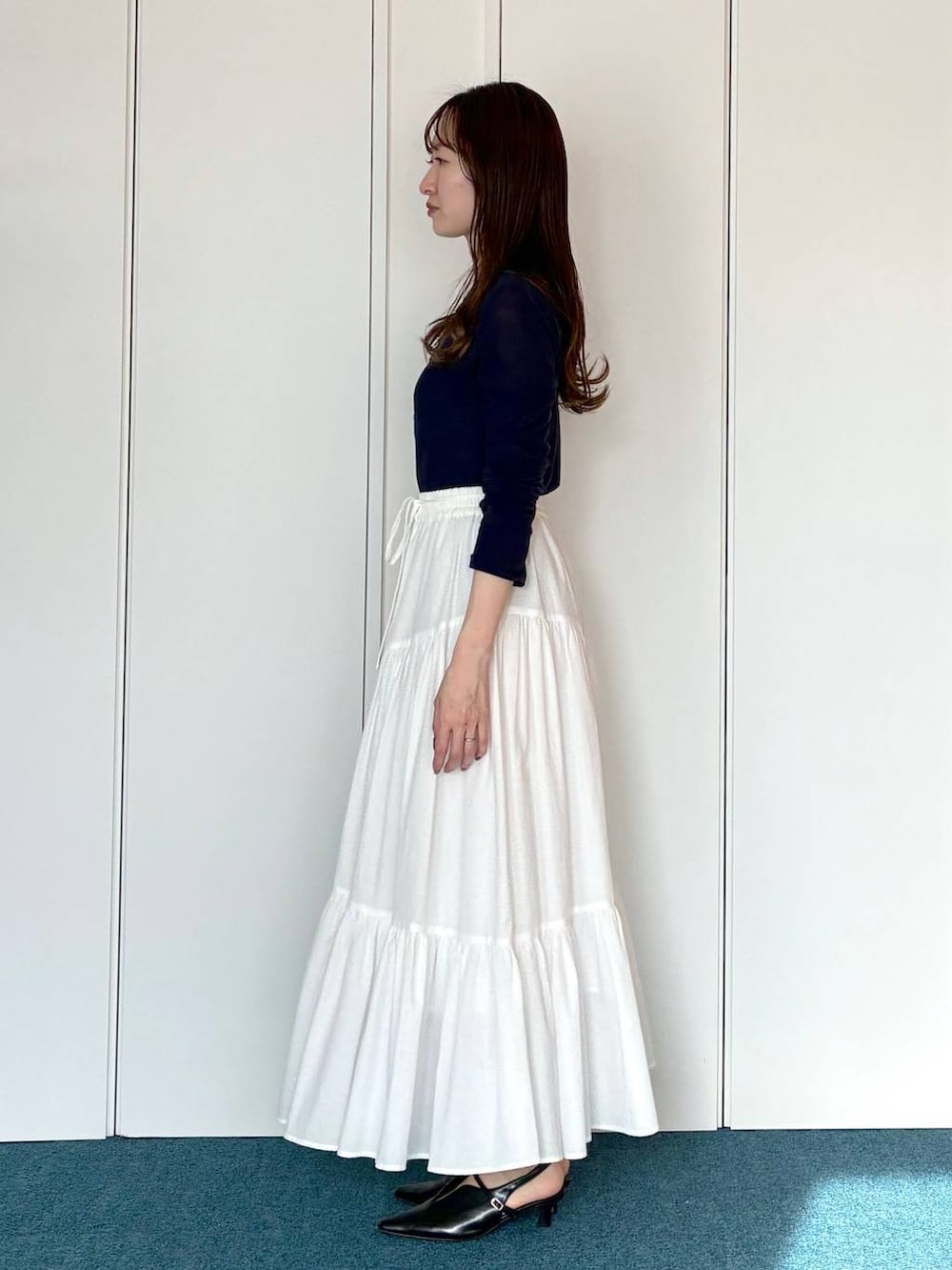 ブラック系のサンダル、ブラック系のショルダーバッグ、ホワイト系のスカートを着用したレディースの春コーディネートの2枚目の写真