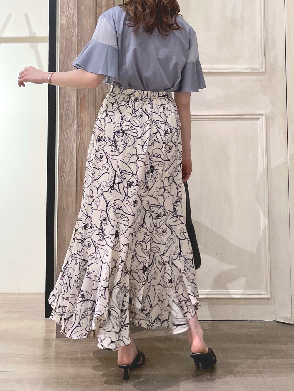 ブルー系のTシャツ/カットソー、ホワイト系のスカート、ブラック系のハンドバッグを着用したレディースの夏コーディネートの3枚目の写真