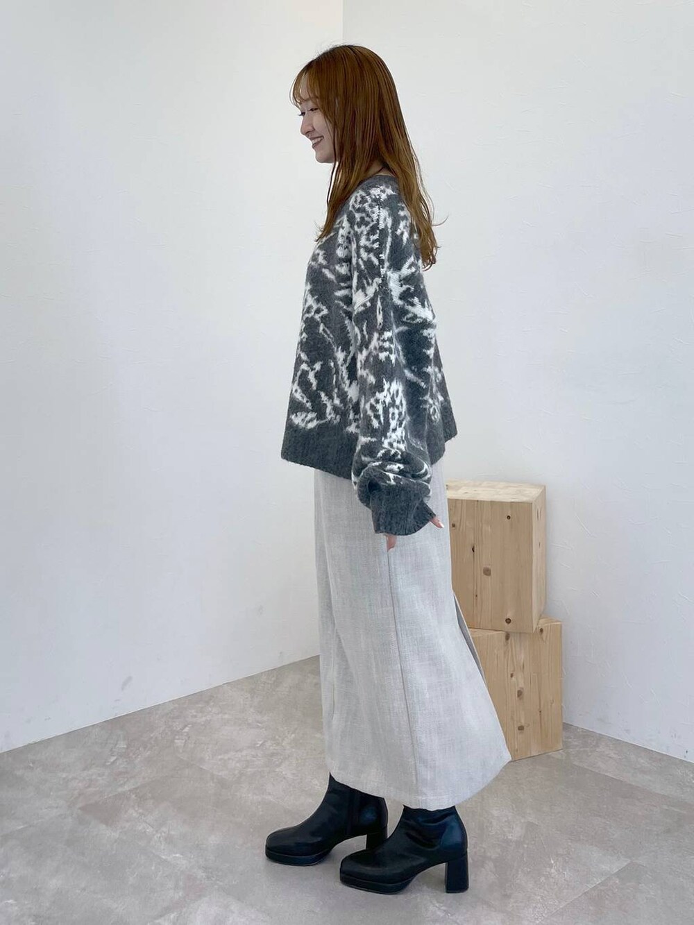 ブラック系のブーツ、ピンク系のハンドバッグ、ホワイト系のスカートを着用したレディースの冬コーディネートの2枚目の写真