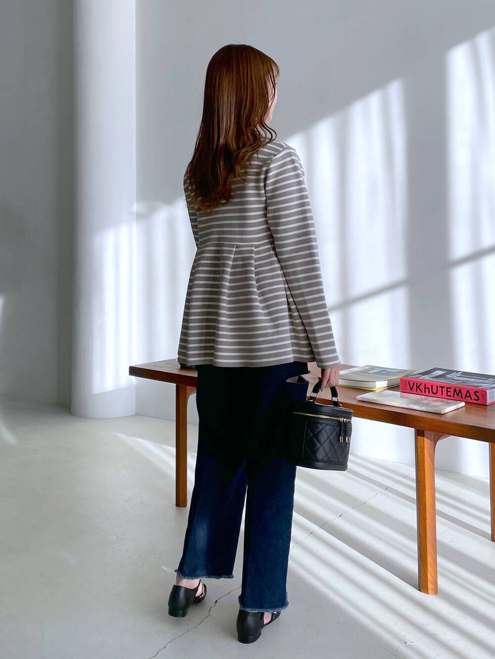 ベージュ系のカーディガン/ボレロ、ブラック系のショルダーバッグ、ブルー系のデニムパンツを着用したレディースの冬コーディネートの2枚目の写真