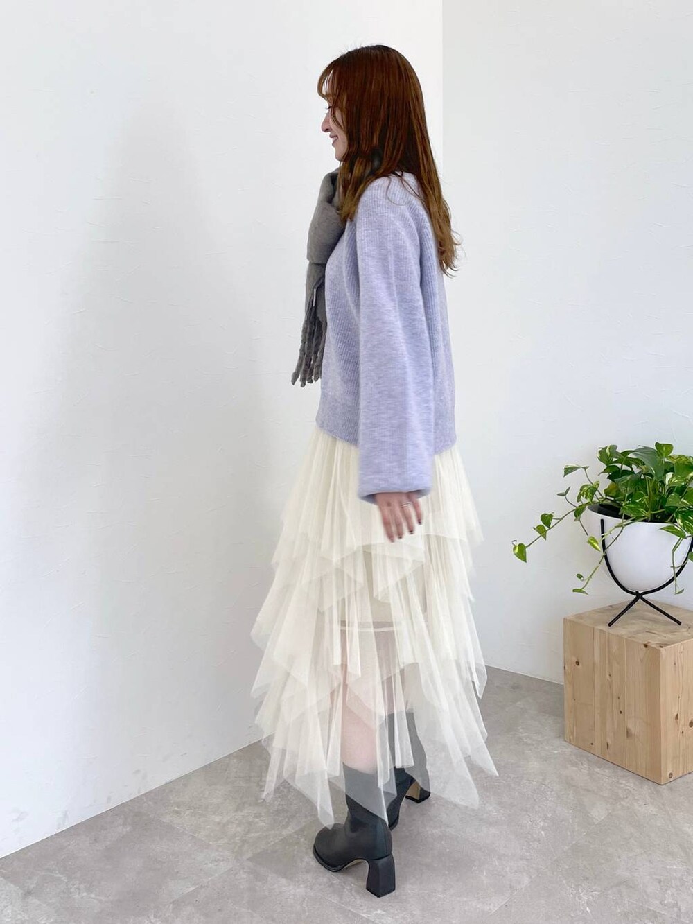 パープル系のニット/セーター、グレー系のブーツ、ホワイト系のショルダーバッグを着用したレディースの冬コーディネートの2枚目の写真