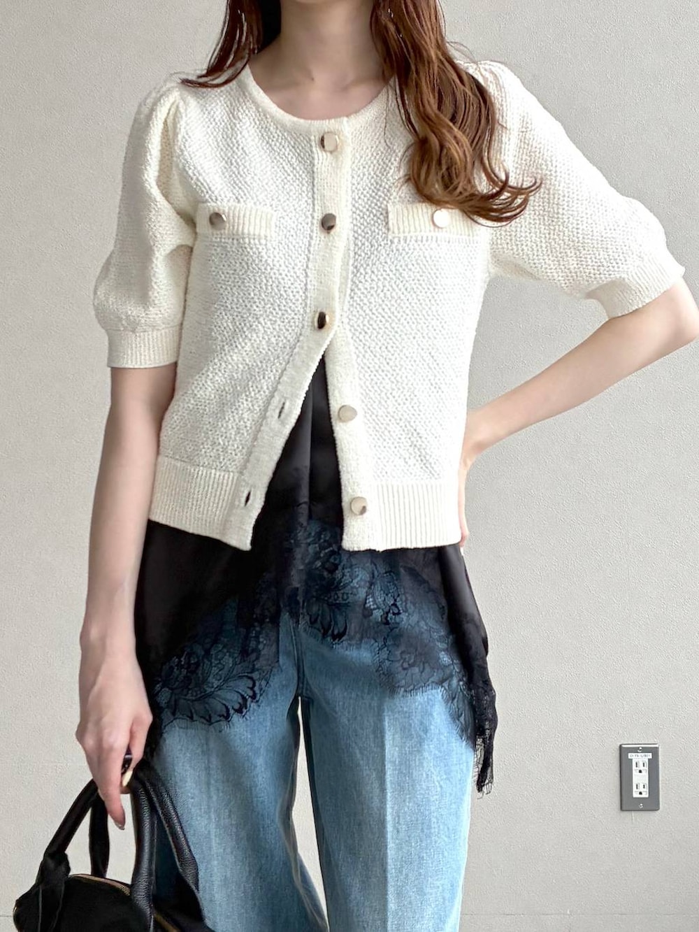 ブラック系のボストンバッグ、ホワイト系のカーディガン/ボレロ、ブラック系のパンプスを着用したレディースの春コーディネートの6枚目の写真