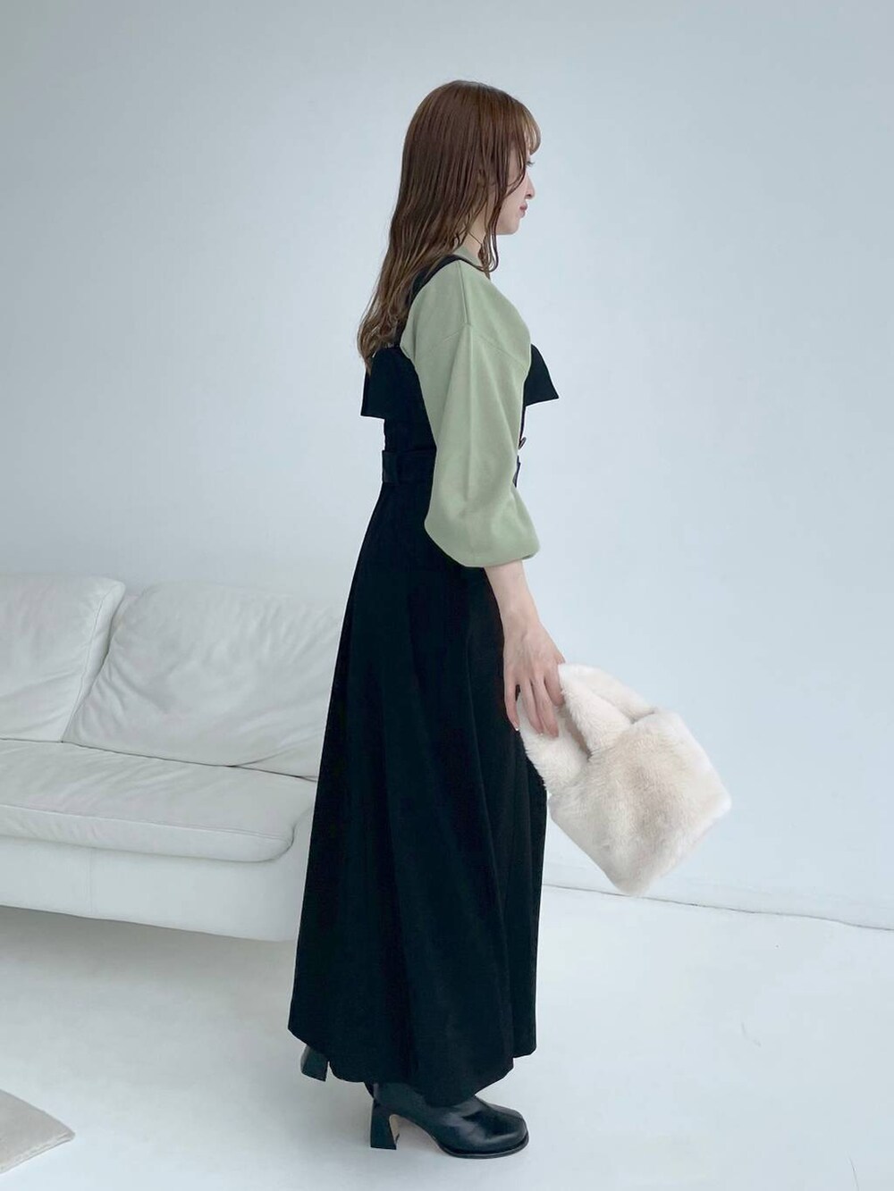 ブラック系のブーツ、ブラック系のジャンパースカート、グリーン系のニット/セーターを着用したレディースの秋コーディネートの4枚目の写真