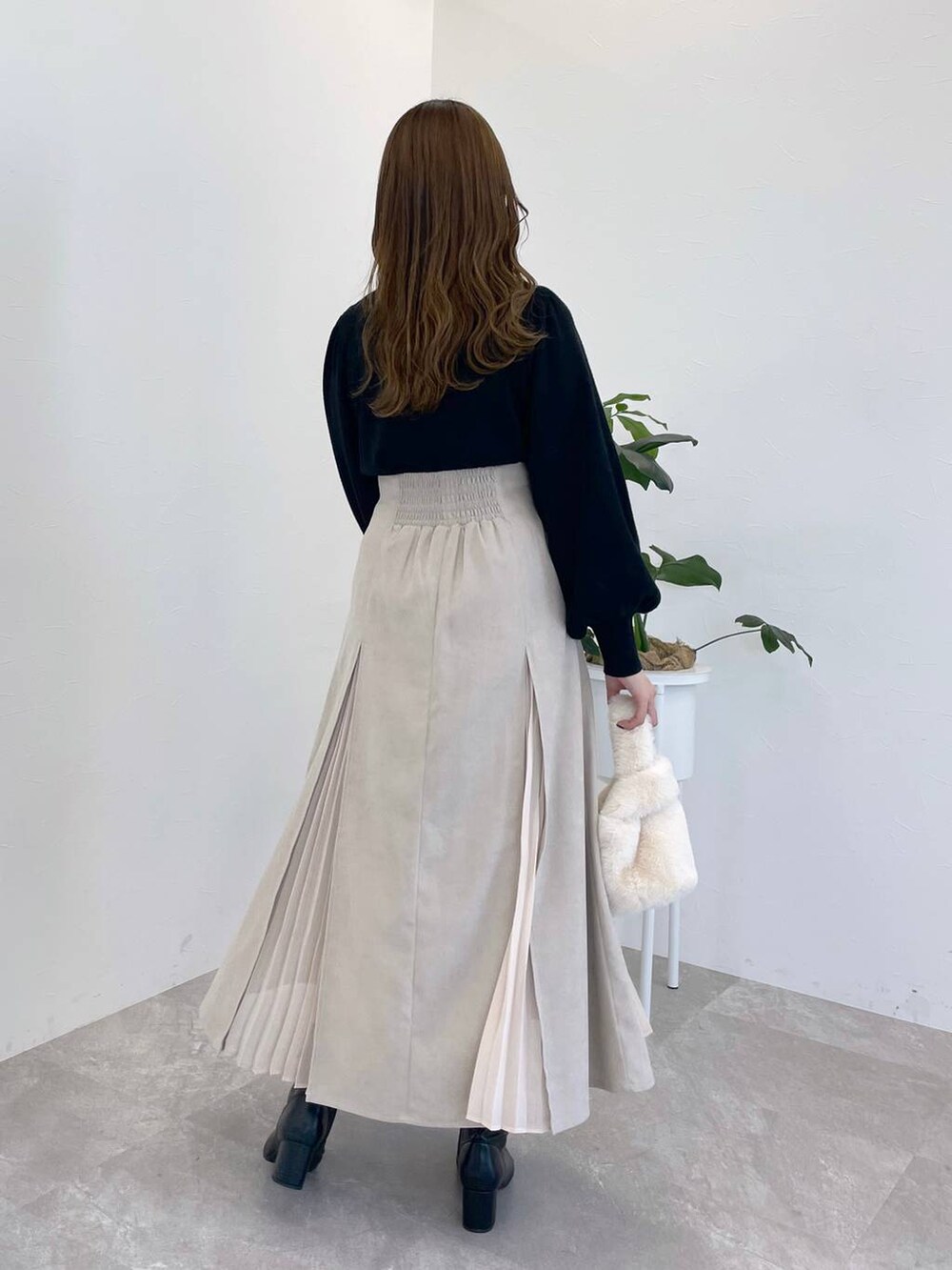 ブラック系のニット/セーター、ブラック系のブーツ、ホワイト系のハンドバッグを着用したレディースの冬コーディネートの2枚目の写真