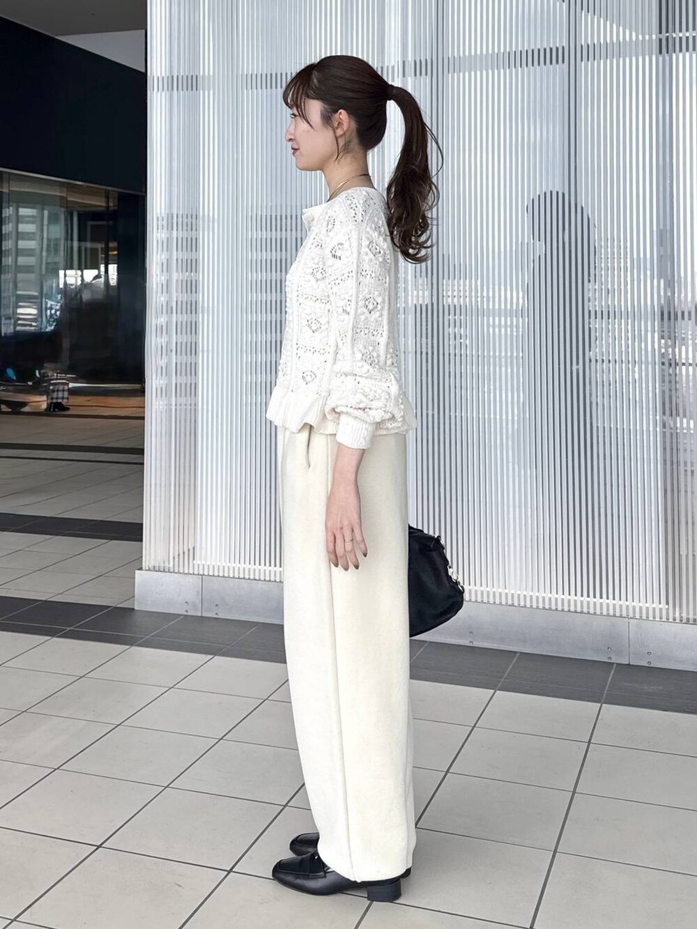 ブラック系のボストンバッグ、ブラック系のローファー、ホワイト系のカーディガン/ボレロを着用したレディースの冬コーディネートの2枚目の写真