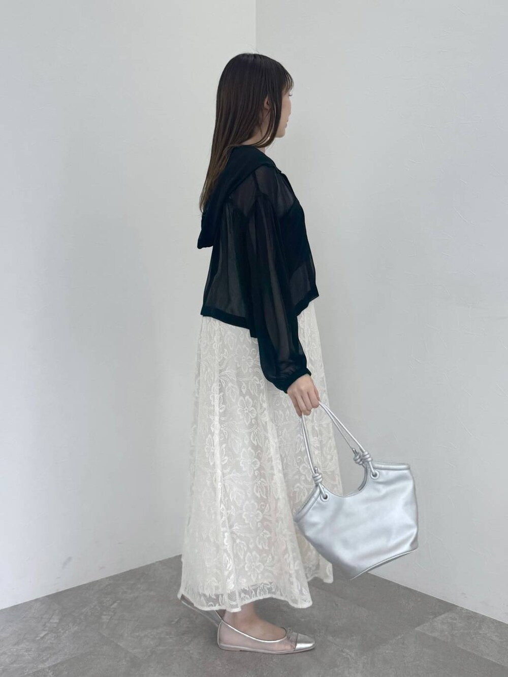 シルバー系のバレエシューズ、ホワイト系のワンピース、ブラック系のパーカーを着用したレディースの春コーディネートの2枚目の写真