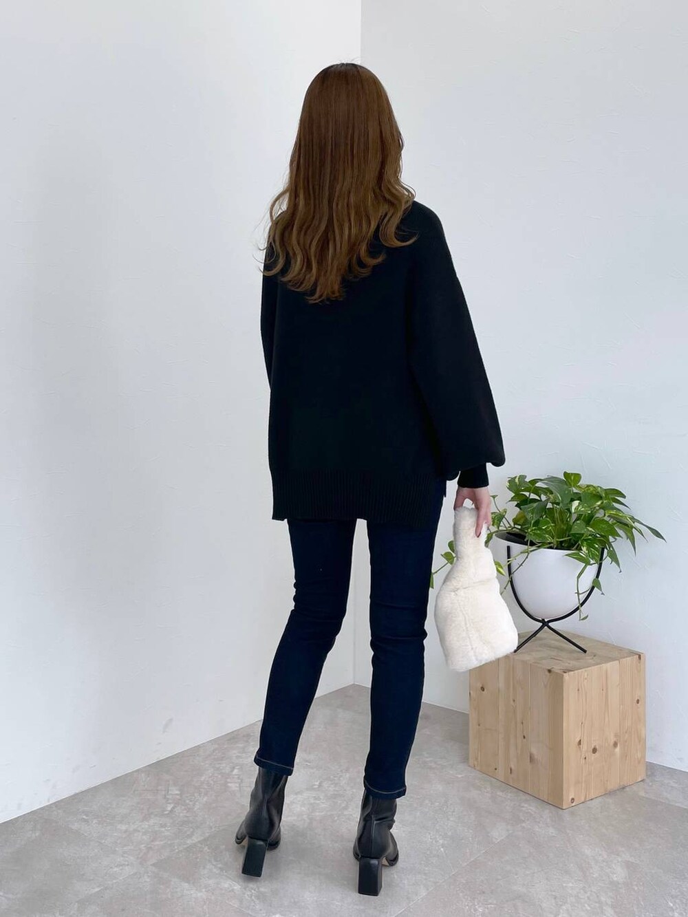 ブルー系のデニムパンツ、ブラック系のブーツ、ホワイト系のハンドバッグを着用したレディースの冬コーディネートの2枚目の写真