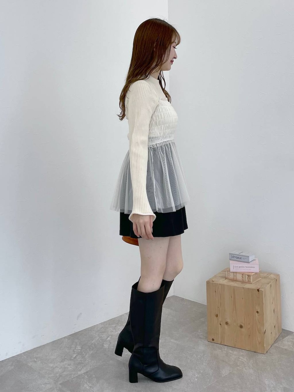 ブラック系のブーツ、オレンジ系のショルダーバッグ、ブラック系のその他パンツを着用したレディースの冬コーディネートの2枚目の写真