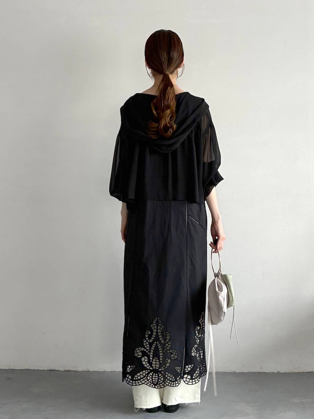 ブラック系のパーカー、ブラック系のパンプス、グリーン系のハンドバッグを着用したレディースの春コーディネートの3枚目の写真