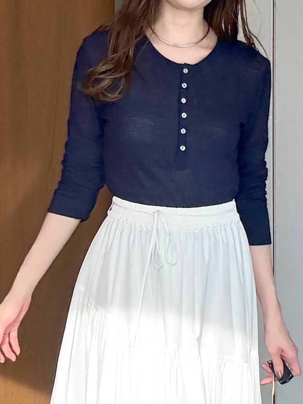 ブラック系のサンダル、ブラック系のショルダーバッグ、ホワイト系のスカートを着用したレディースの春コーディネートの5枚目の写真