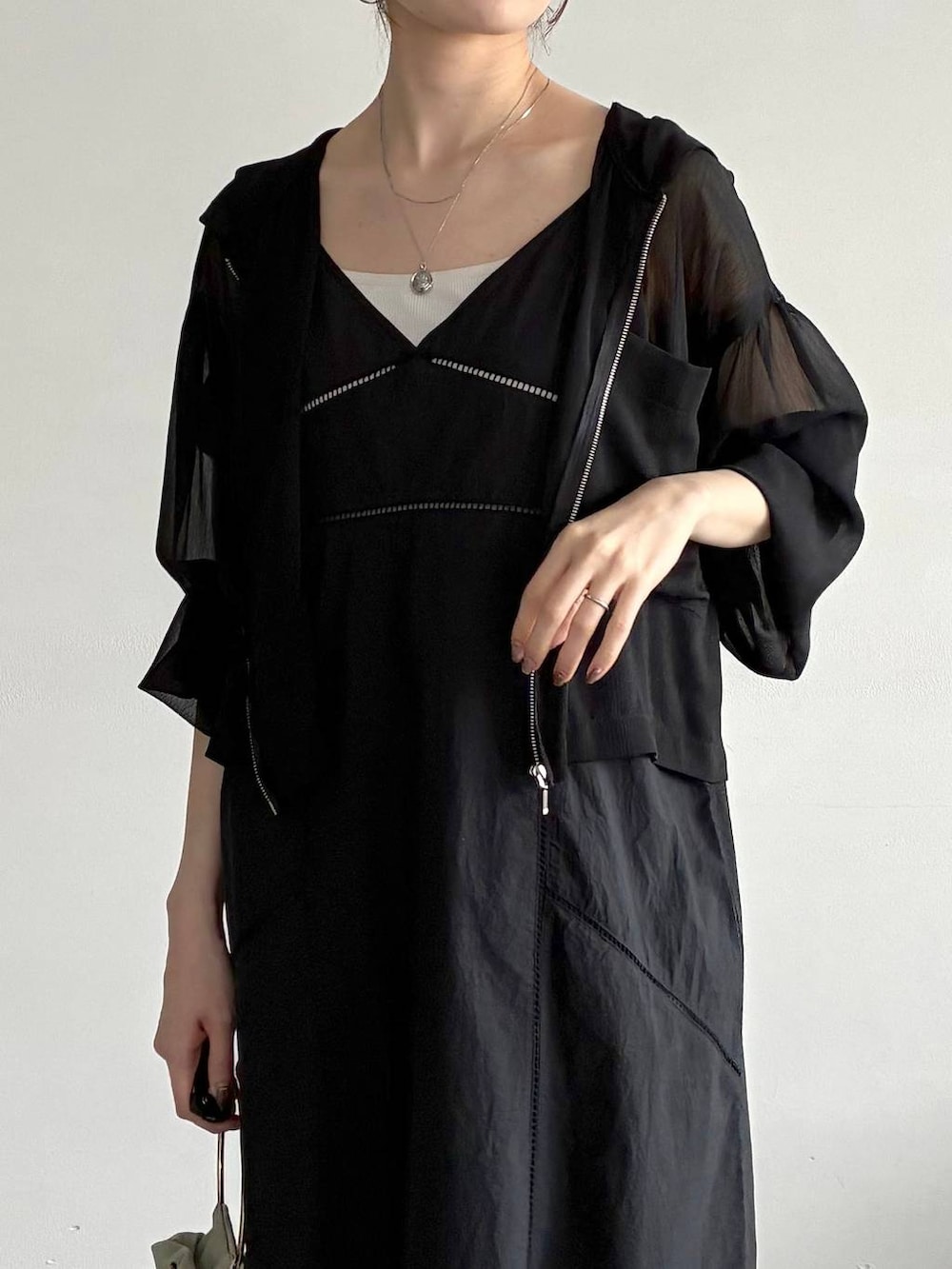 ブラック系のパーカー、ブラック系のパンプス、グリーン系のハンドバッグを着用したレディースの春コーディネートの6枚目の写真