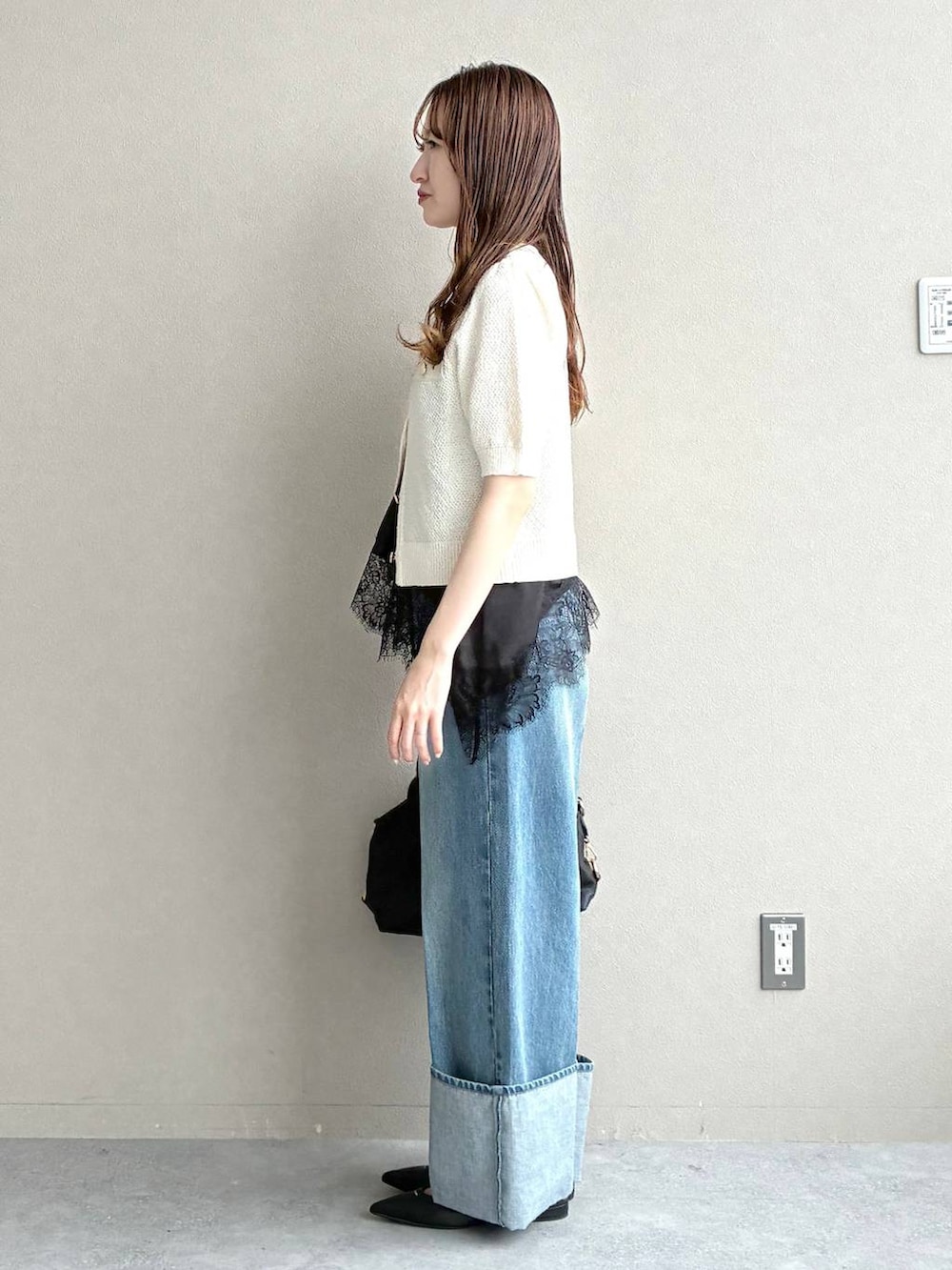 ブラック系のボストンバッグ、ホワイト系のカーディガン/ボレロ、ブラック系のパンプスを着用したレディースの春コーディネートの2枚目の写真