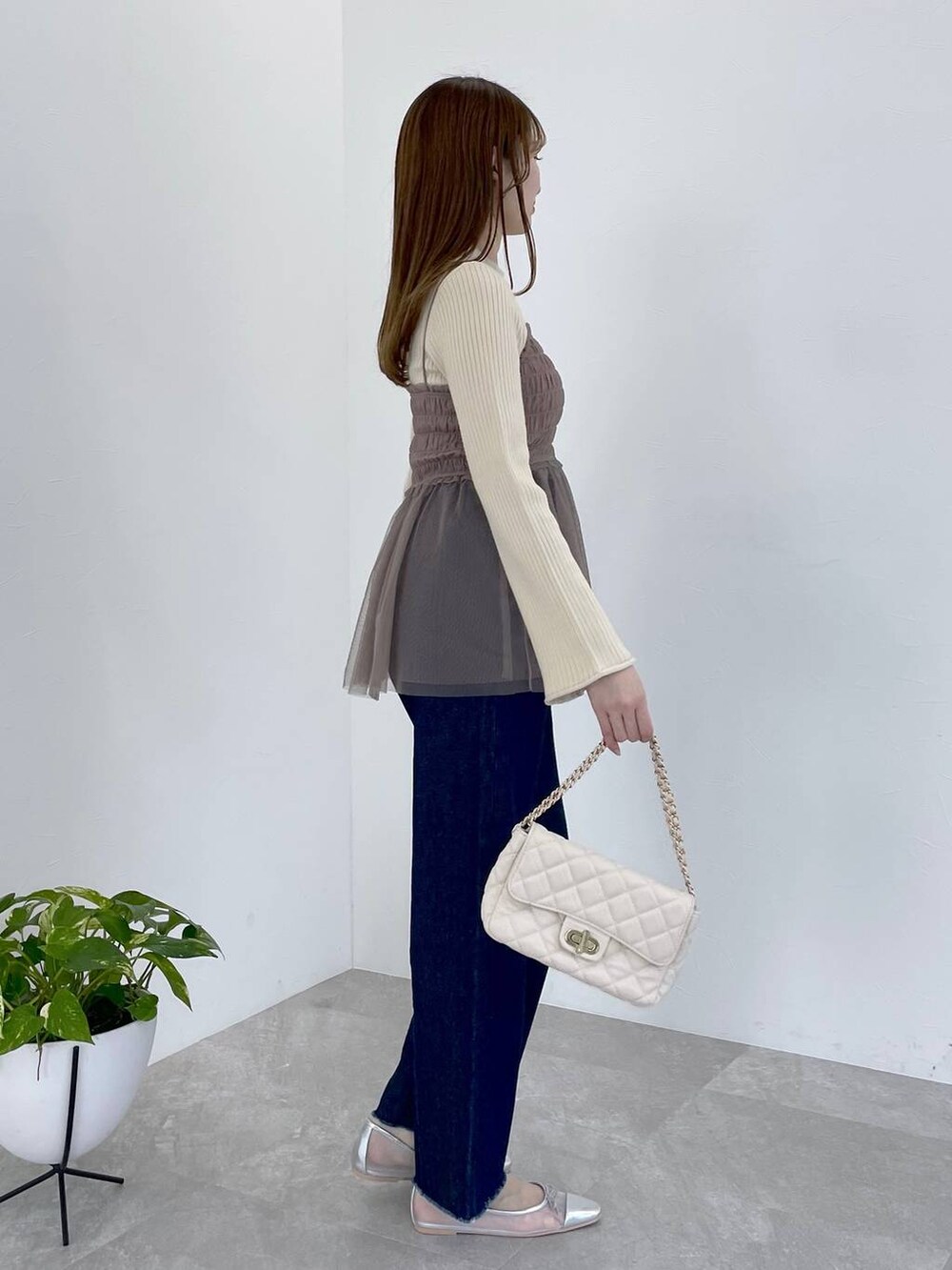 シルバー系のバレエシューズ、ホワイト系のショルダーバッグ、ブラウン系のニット/セーターを着用したレディースの春コーディネートの2枚目の写真