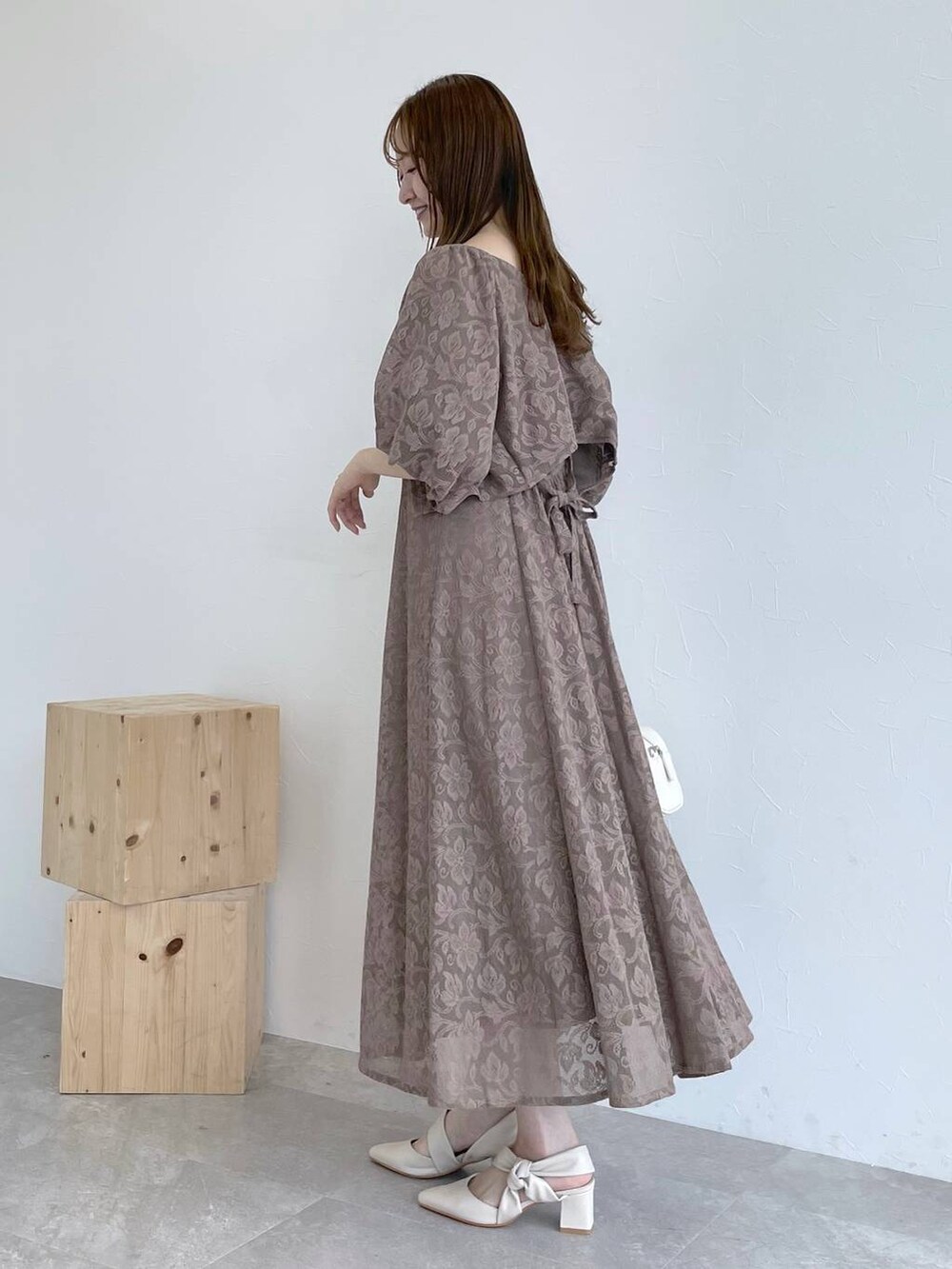 ホワイト系のボストンバッグ、ブラウン系のワンピース、ホワイト系のパンプスを着用したレディースの秋コーディネートの4枚目の写真