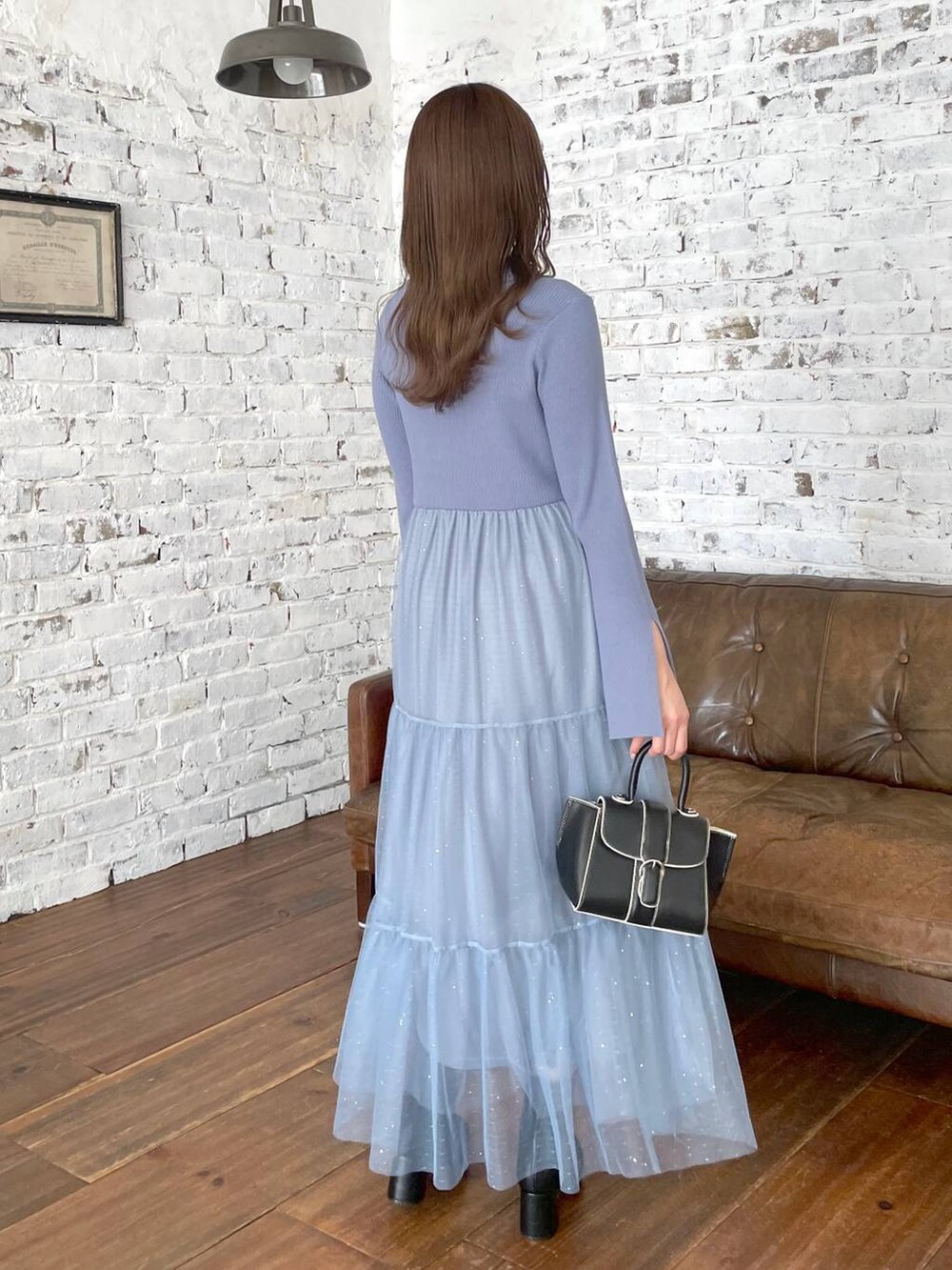 ブラック系のハンドバッグ、ブラック系のブーツ、ブルー系のワンピースを着用したレディースの秋コーディネートの3枚目の写真