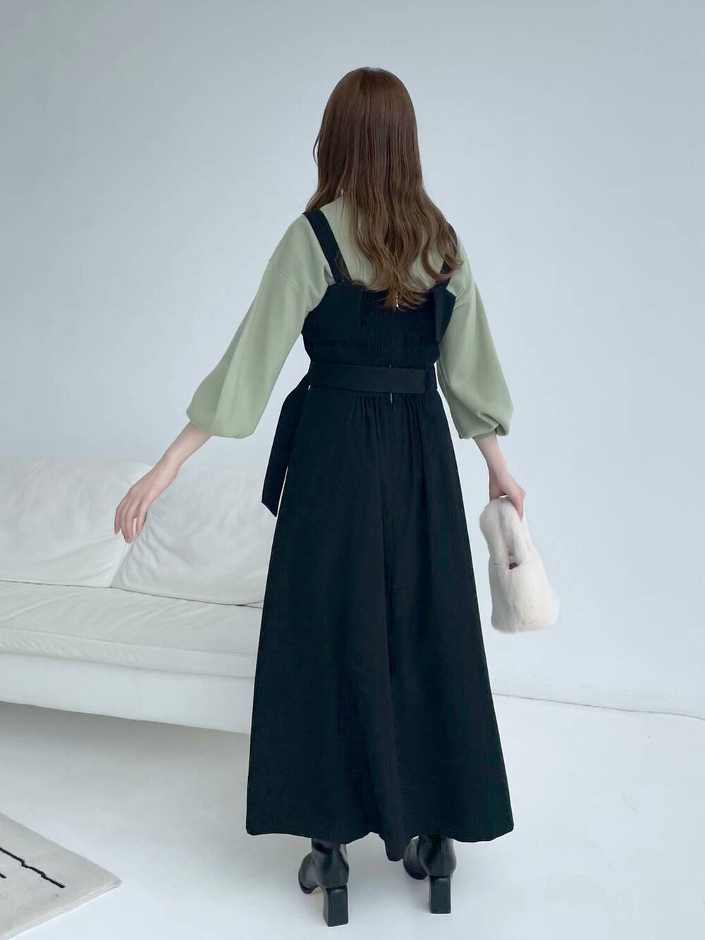 ブラック系のブーツ、ブラック系のジャンパースカート、グリーン系のニット/セーターを着用したレディースの秋コーディネートの3枚目の写真