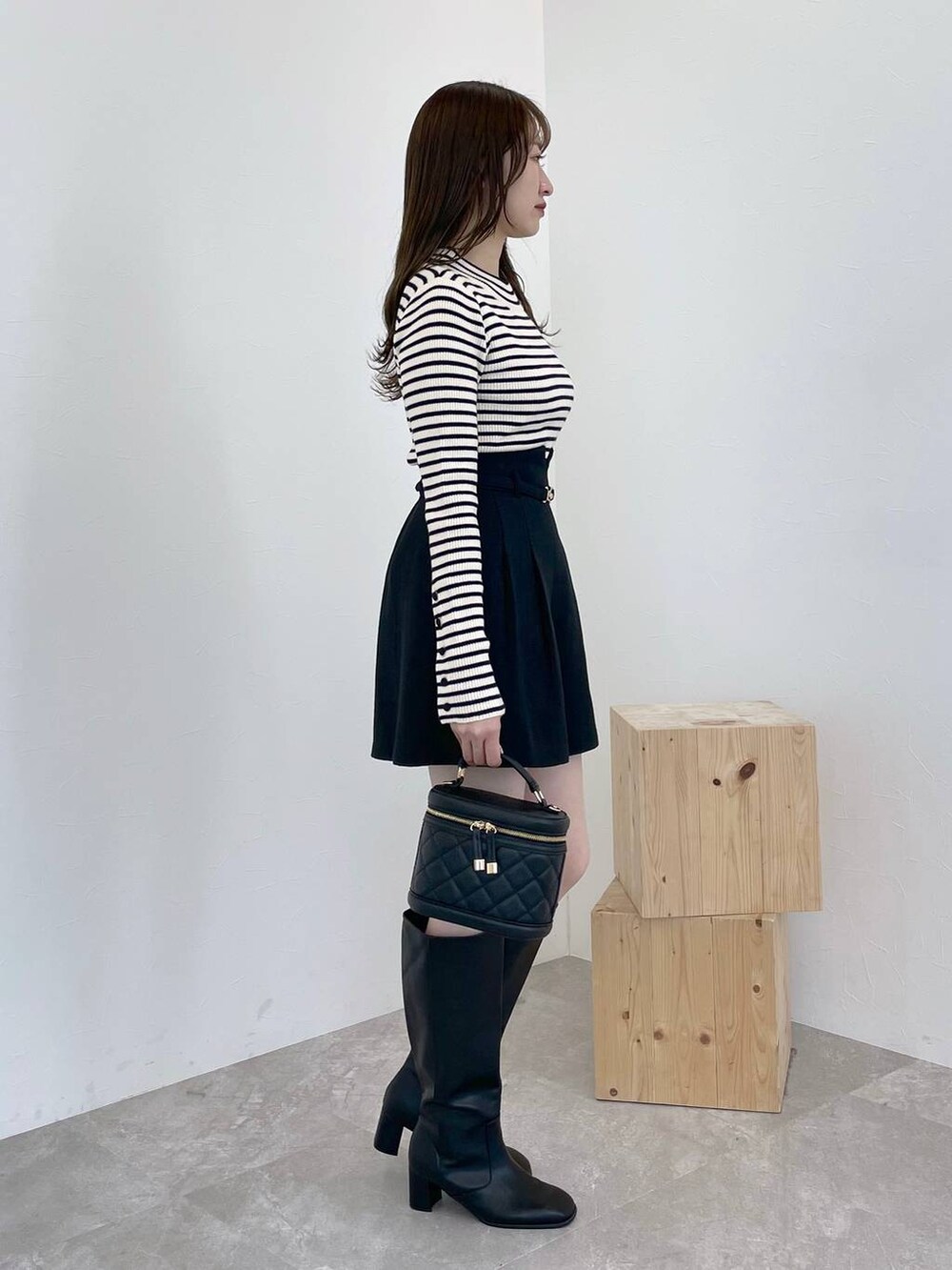 ブラック系のブーツ、ホワイト系のニット/セーター、ブラック系のショルダーバッグを着用したレディースの冬コーディネートの4枚目の写真