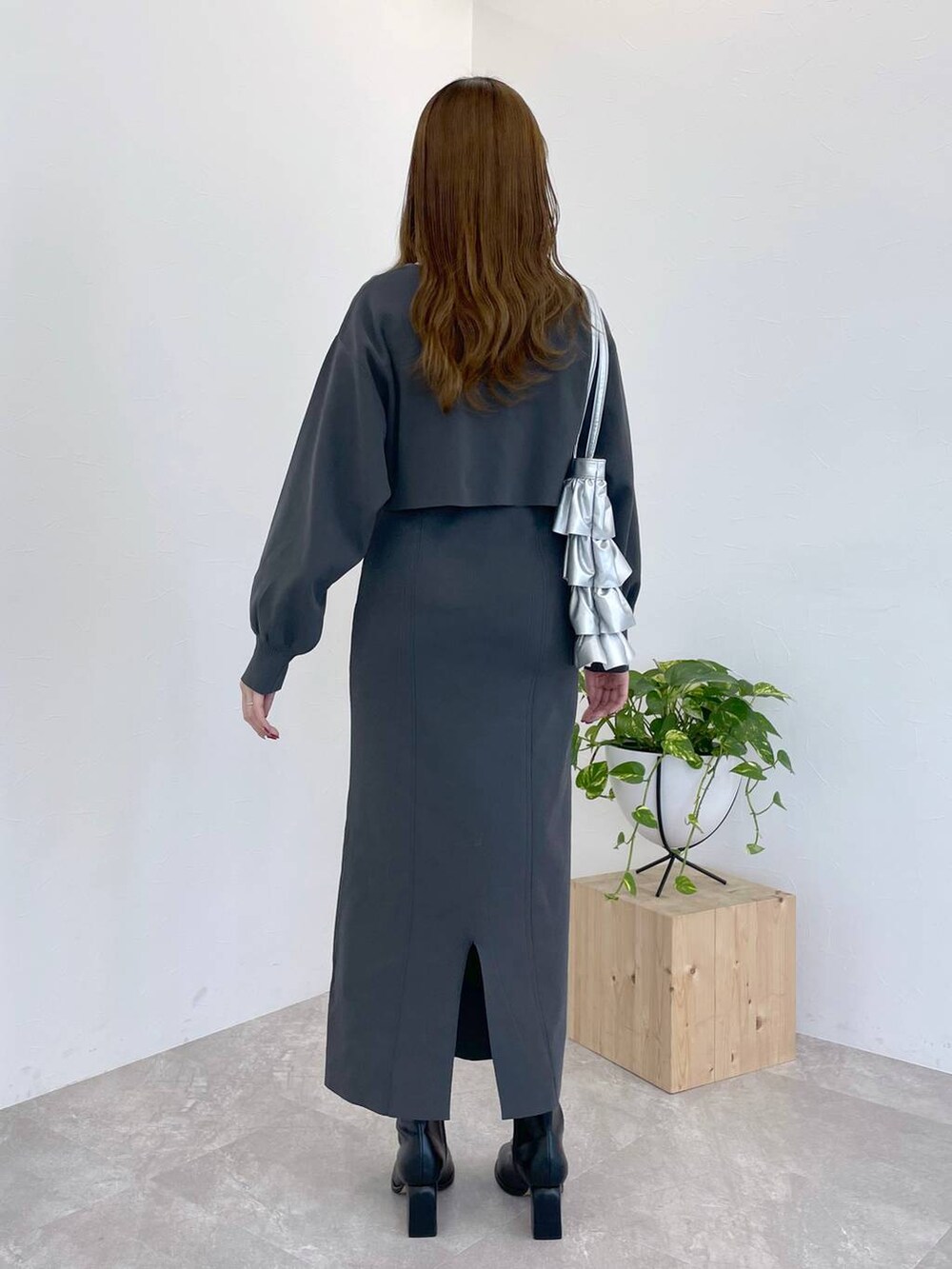 ブラック系のブーツ、シルバー系のトートバッグ、グレー系のワンピースを着用したレディースの冬コーディネートの2枚目の写真