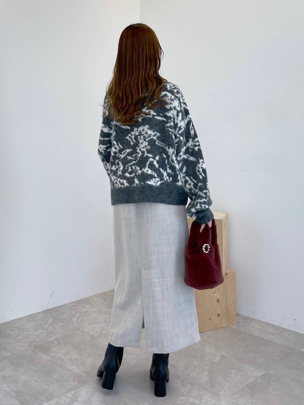 ブラック系のブーツ、ピンク系のハンドバッグ、ホワイト系のスカートを着用したレディースの冬コーディネートの3枚目の写真