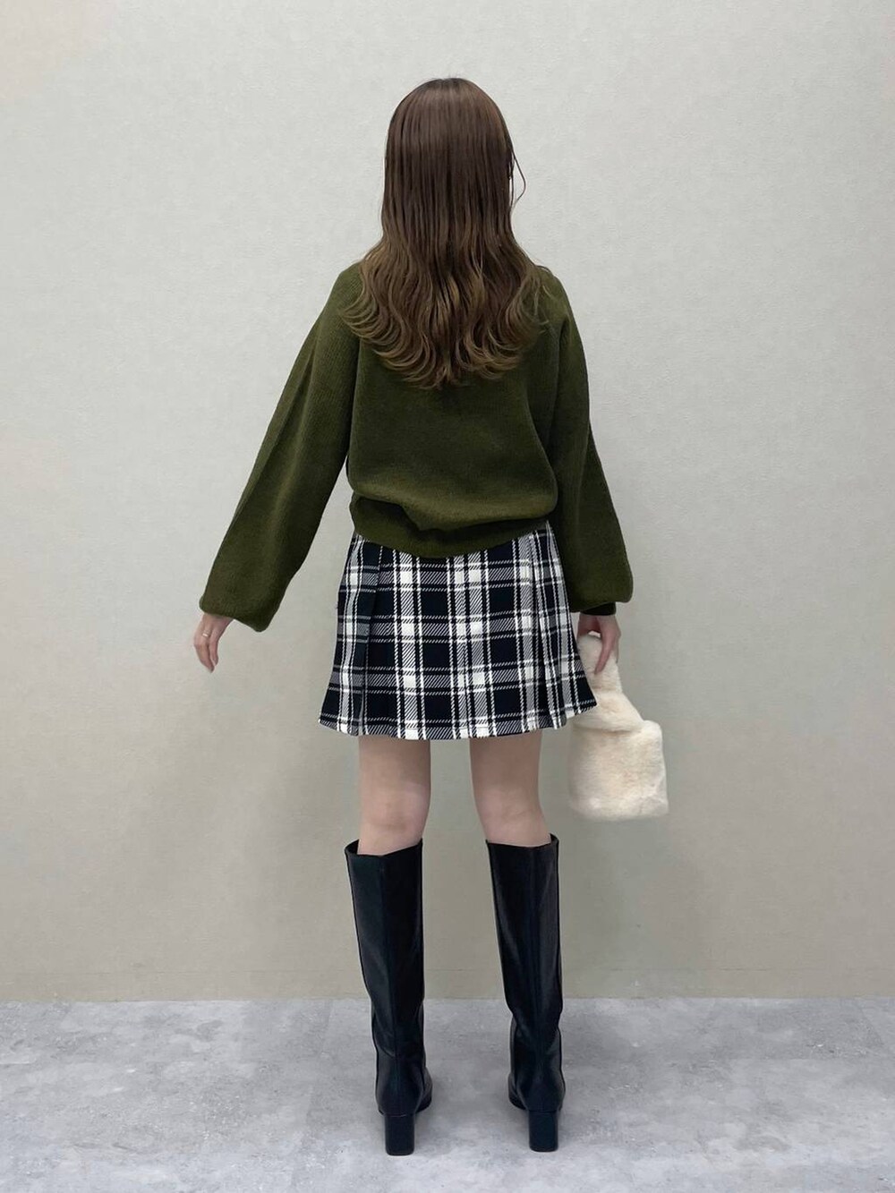 グリーン系のニット/セーター、ホワイト系のチェスターコート、ブラック系のブーツを着用したレディースの秋コーディネートの6枚目の写真