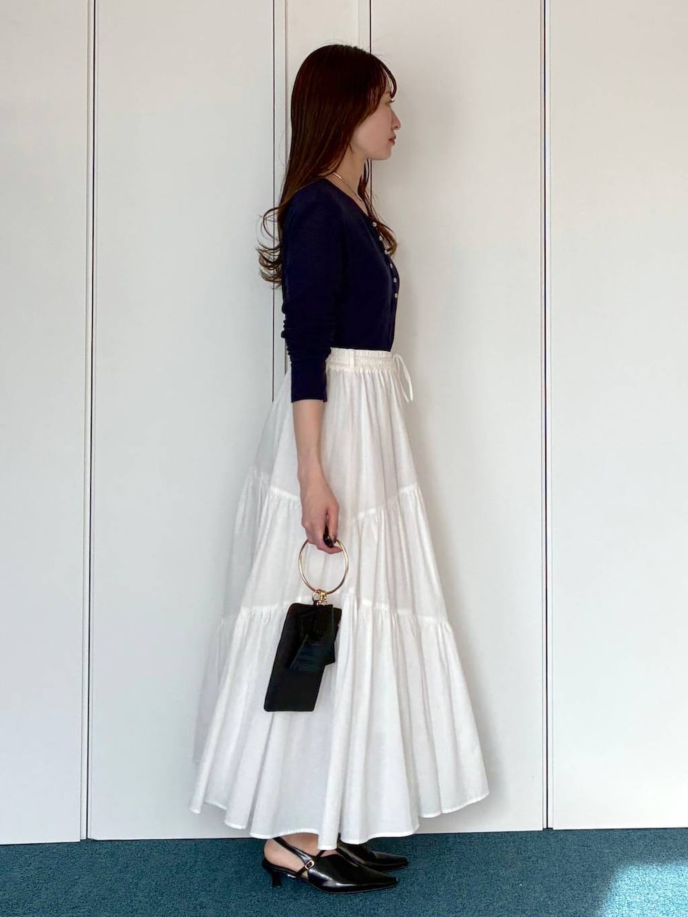 ブラック系のサンダル、ブラック系のショルダーバッグ、ホワイト系のスカートを着用したレディースの春コーディネートの4枚目の写真