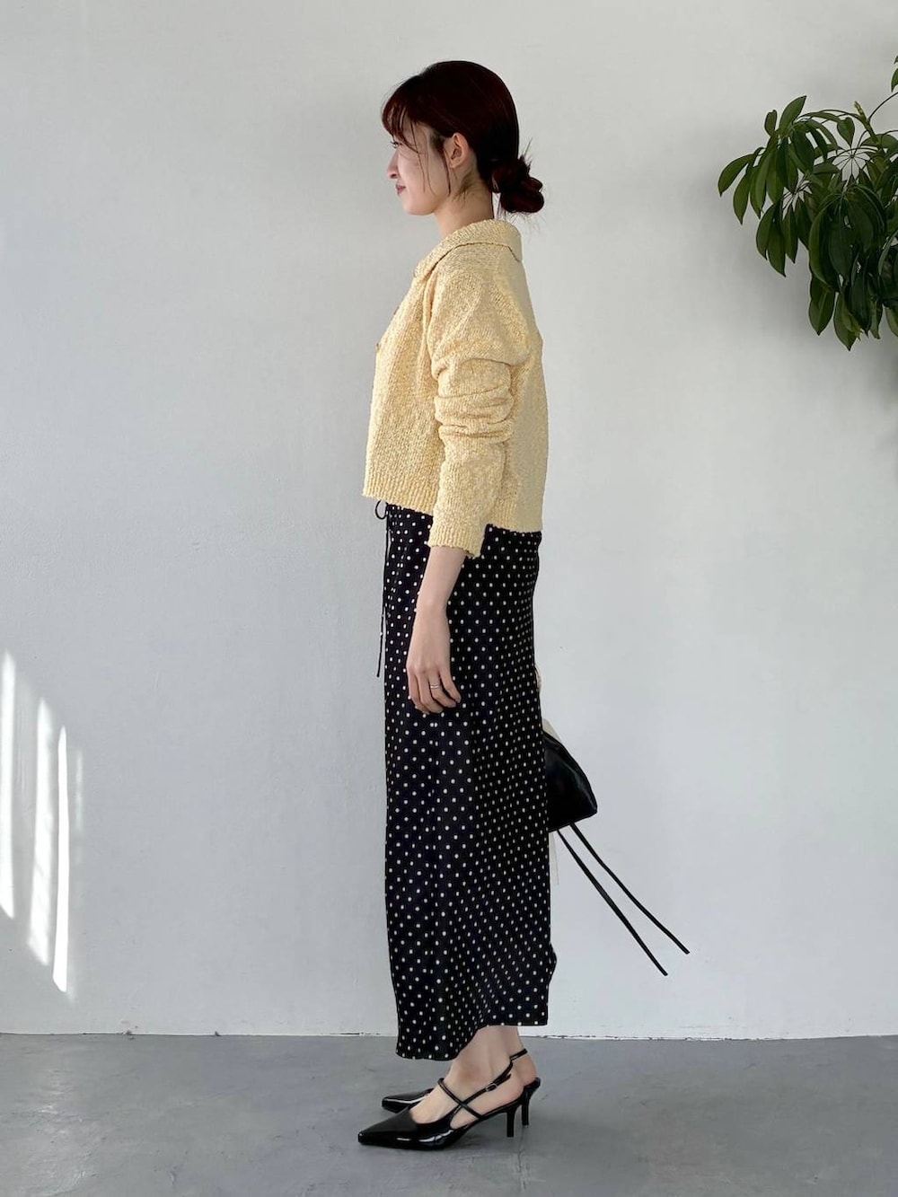 ブラック系のサンダル、イエロー系のカーディガン/ボレロ、ブラック系のスカートを着用したレディースの冬コーディネートの2枚目の写真