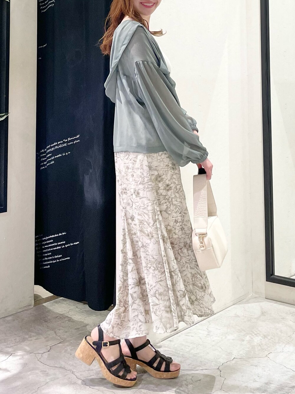 グリーン系のパーカー、ホワイト系のタンクトップ、ホワイト系のスカートを着用したレディースの春コーディネートの4枚目の写真