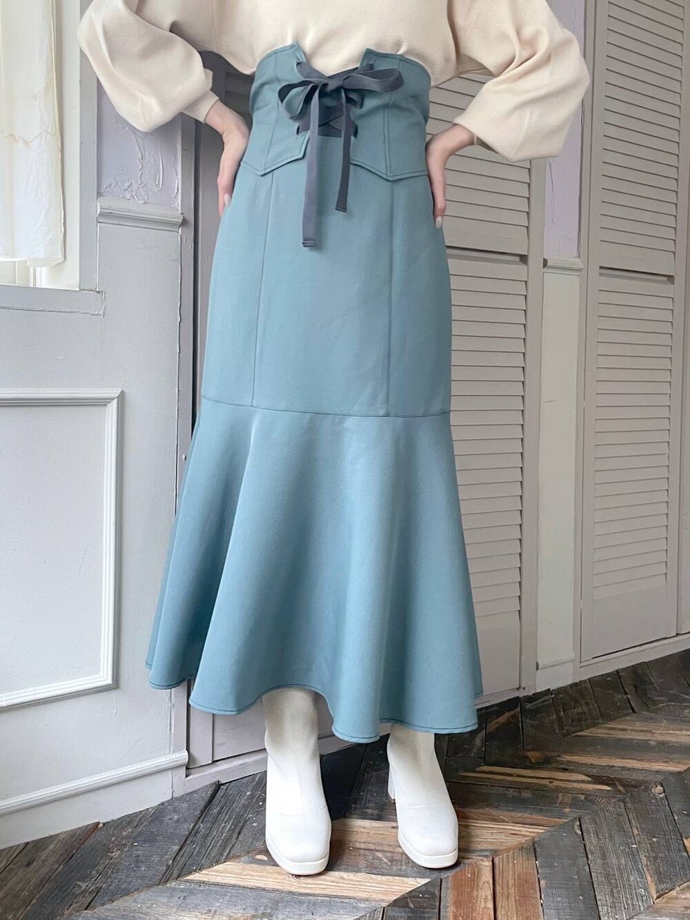 ホワイト系のハンドバッグ、ホワイト系のブーツ、ブルー系のスカートを着用したレディースの秋コーディネートの4枚目の写真