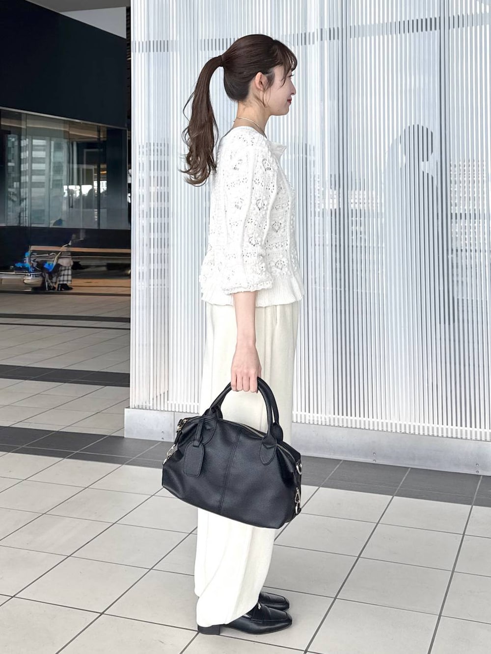 ブラック系のボストンバッグ、ブラック系のローファー、ホワイト系のカーディガン/ボレロを着用したレディースの冬コーディネートの4枚目の写真