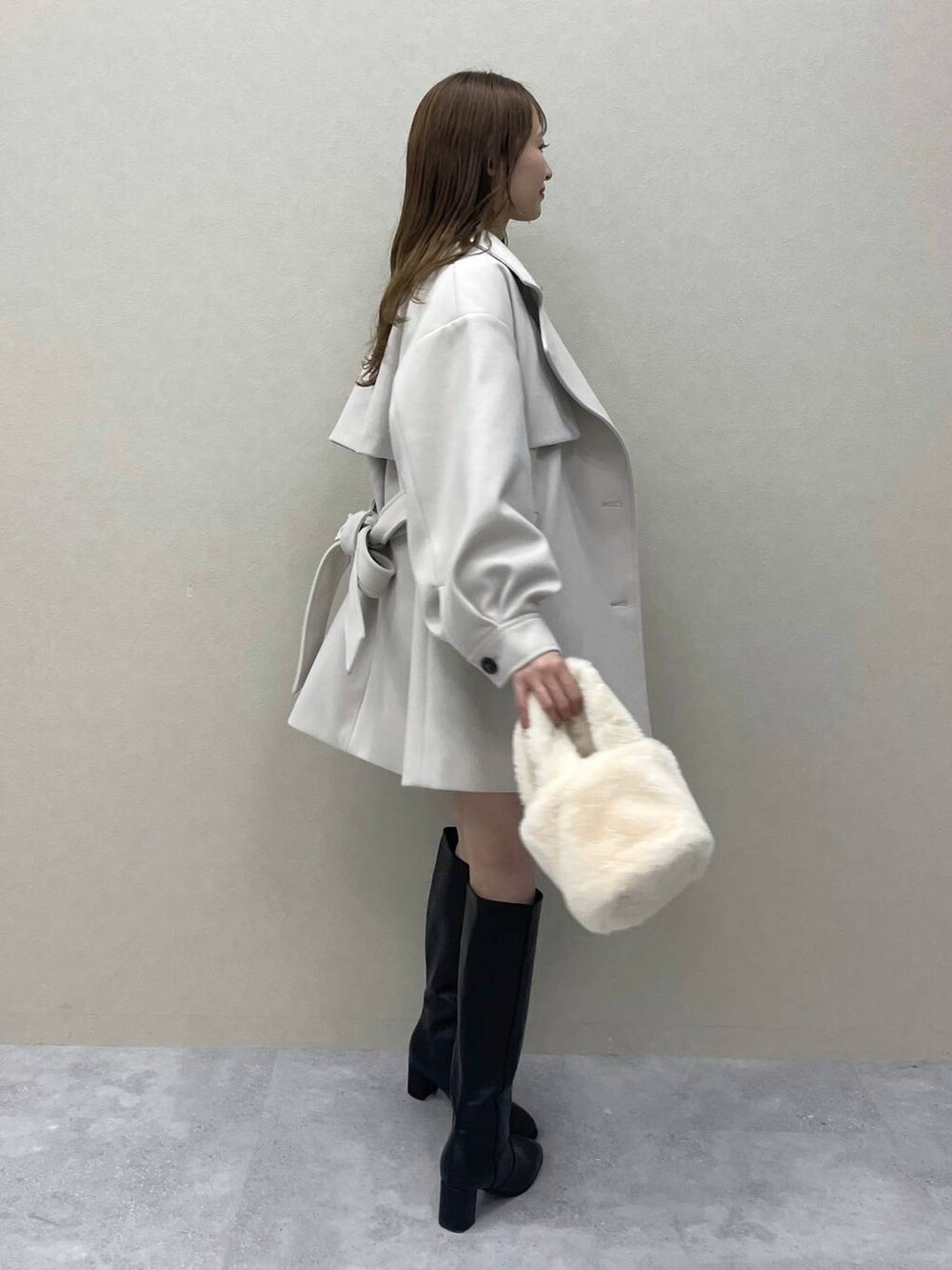 グリーン系のニット/セーター、ホワイト系のチェスターコート、ブラック系のブーツを着用したレディースの秋コーディネートの3枚目の写真