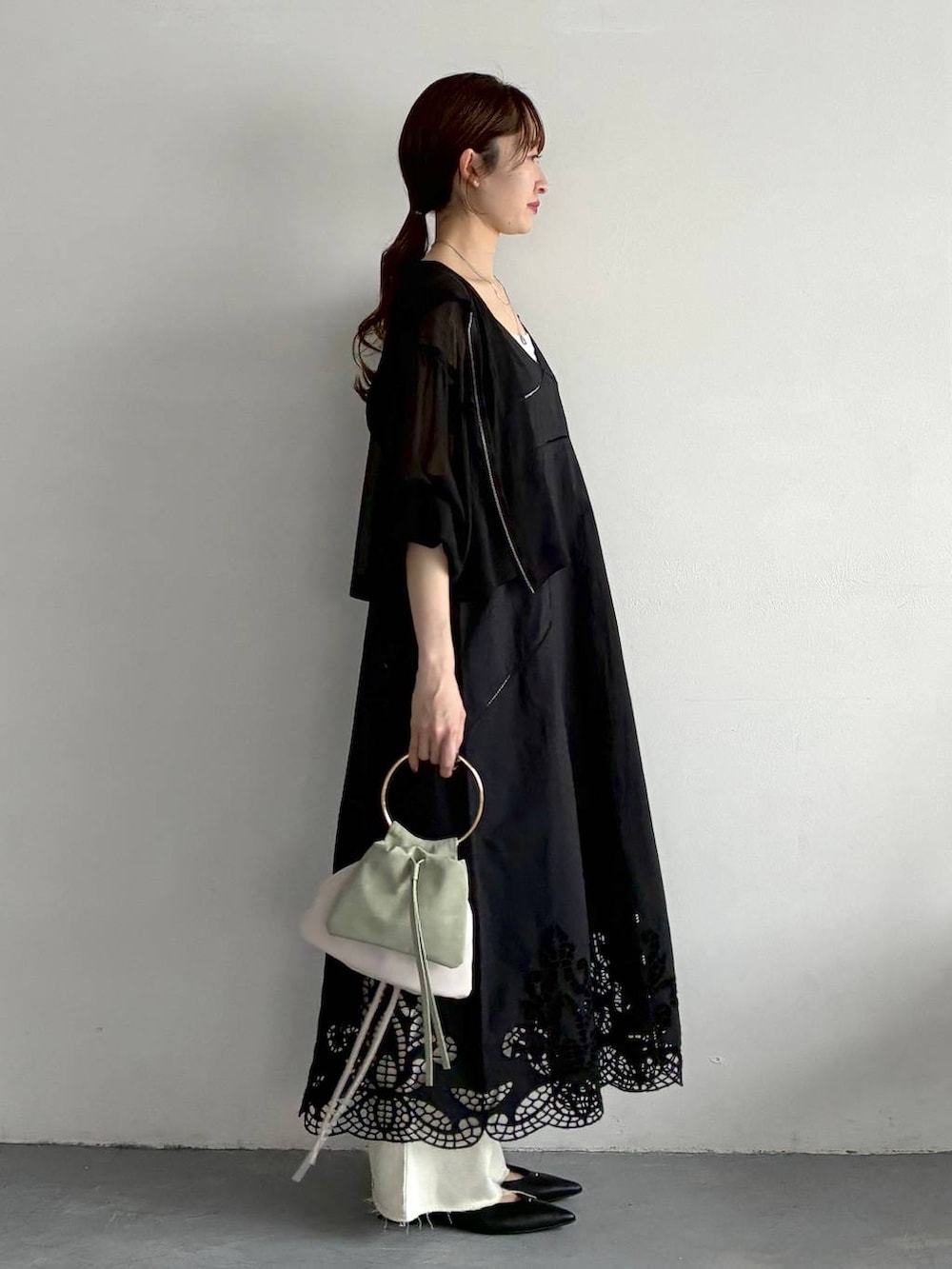 ブラック系のパーカー、ブラック系のパンプス、グリーン系のハンドバッグを着用したレディースの春コーディネートの4枚目の写真