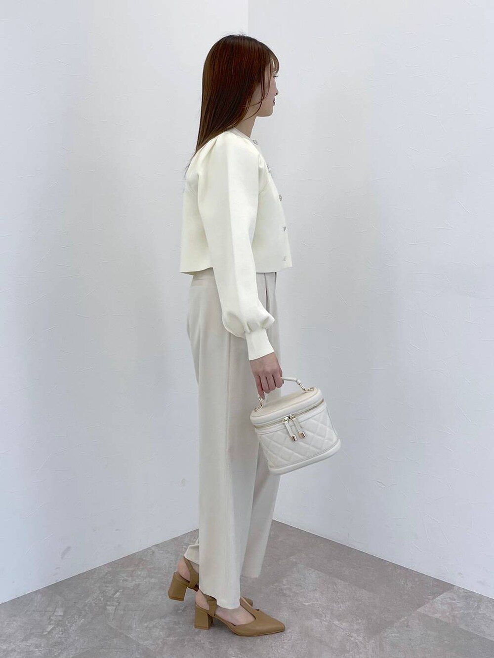 ホワイト系のカーディガン/ボレロ、ホワイト系のショルダーバッグ、ベージュ系のパンプスを着用したレディースの冬コーディネートの2枚目の写真