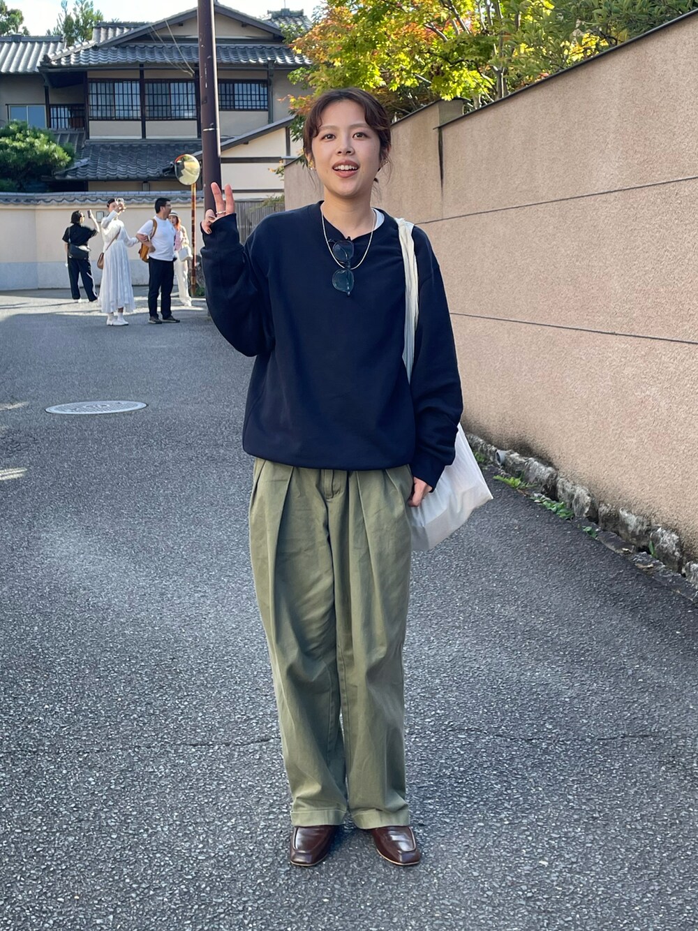 ブルー系のスウェット、グリーン系のチノパンツ、ブラウン系のローファーを着用したレディースの秋コーディネートの2枚目の写真
