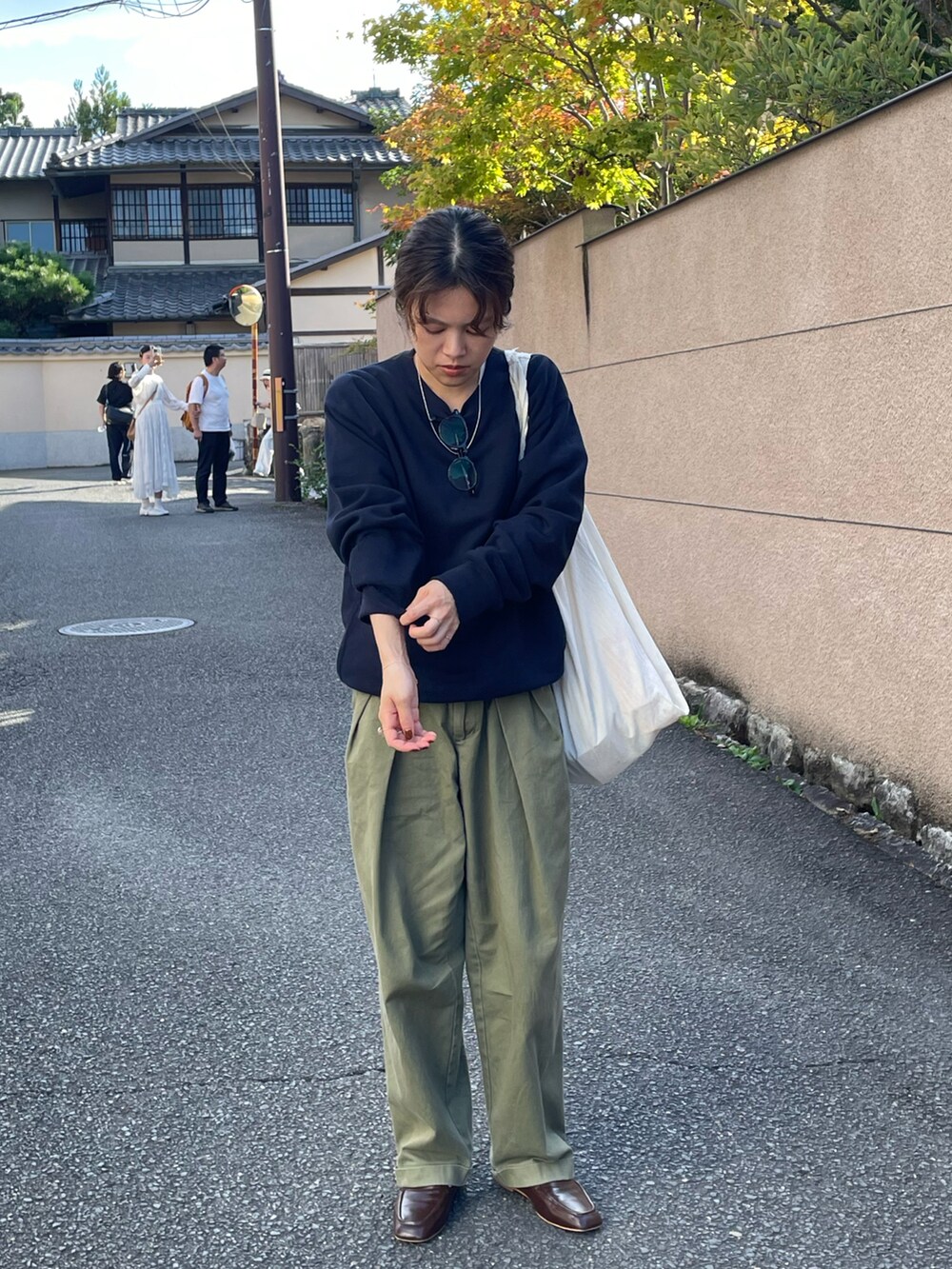 ブルー系のスウェット、グリーン系のチノパンツ、ブラウン系のローファーを着用したレディースの秋コーディネートの3枚目の写真