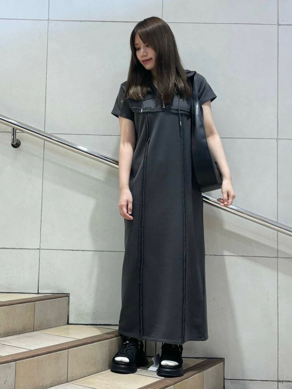 ブラック系のショルダーバッグ、ブラック系のサンダル、グレー系のワンピースを着用したレディースの春コーディネートの3枚目の写真