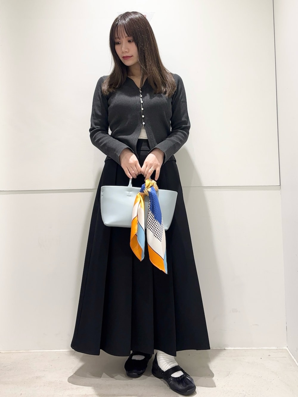 グレー系のカーディガン/ボレロ、ブラック系のスカート、ブルー系のトートバッグを着用したレディースの春コーディネートの3枚目の写真