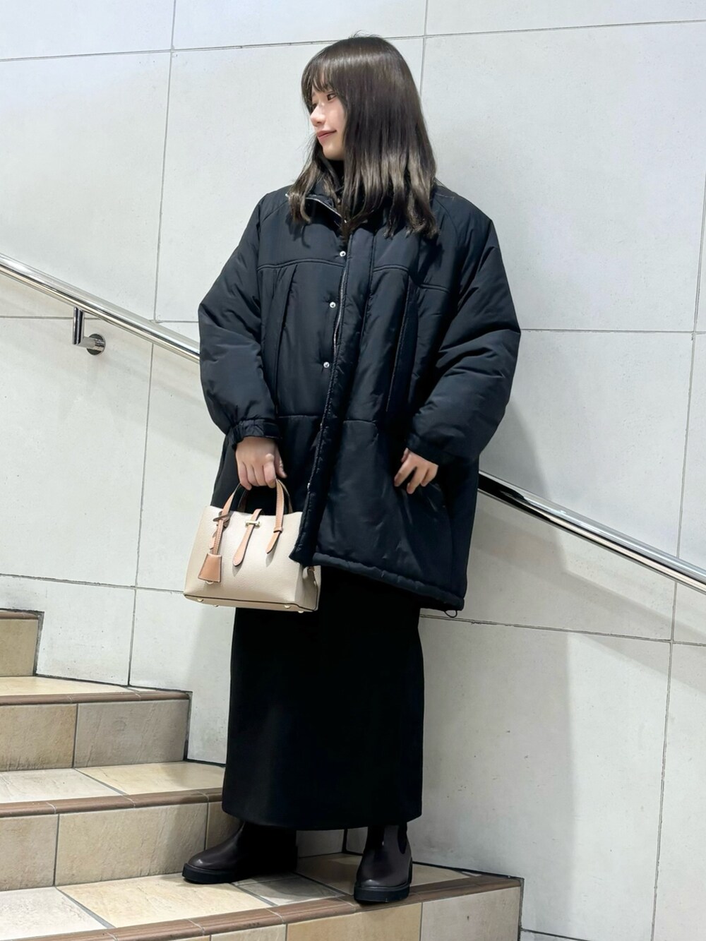 グレー系のニット/セーター、ブラック系のダウンジャケット/コート、グレー系のスカートを着用したレディースの冬コーディネートの4枚目の写真