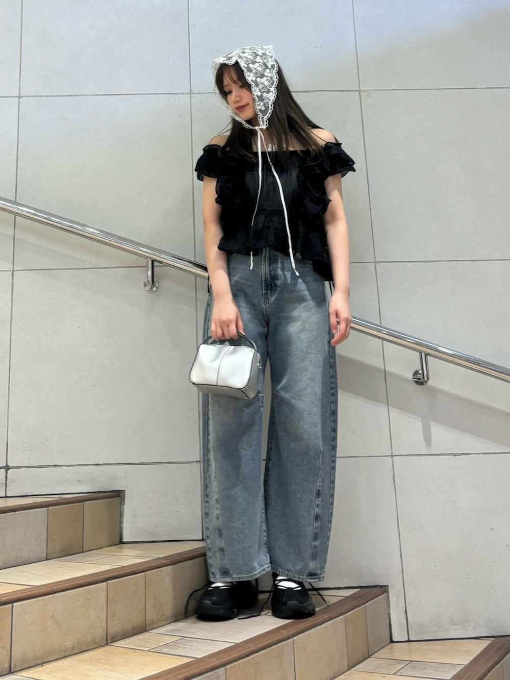 ブラック系のスニーカー、ホワイト系のキャミソール、ブルー系のデニムパンツを着用したレディースの春コーディネートの3枚目の写真