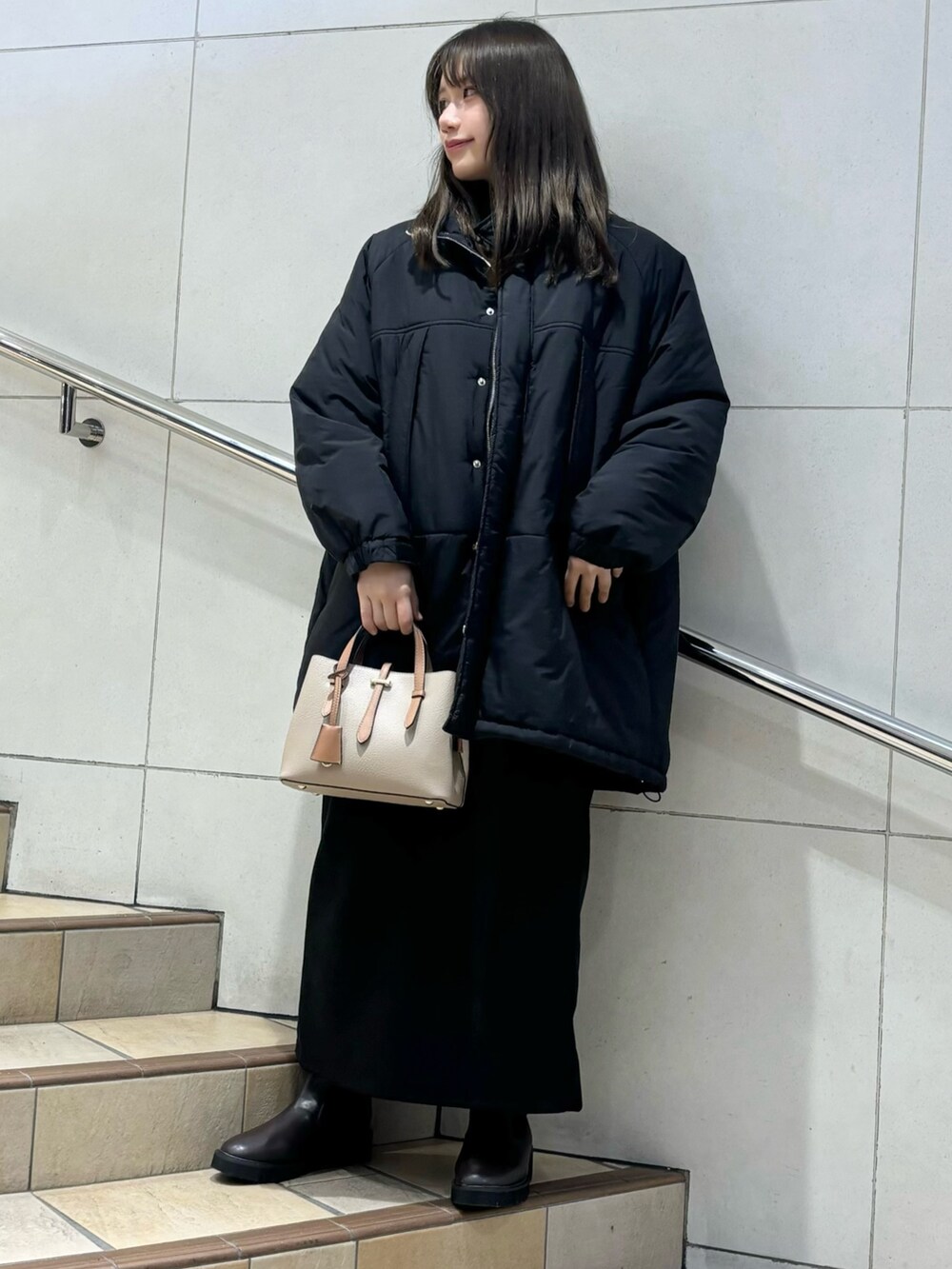 グレー系のニット/セーター、ブラック系のダウンジャケット/コート、グレー系のスカートを着用したレディースの冬コーディネートの3枚目の写真