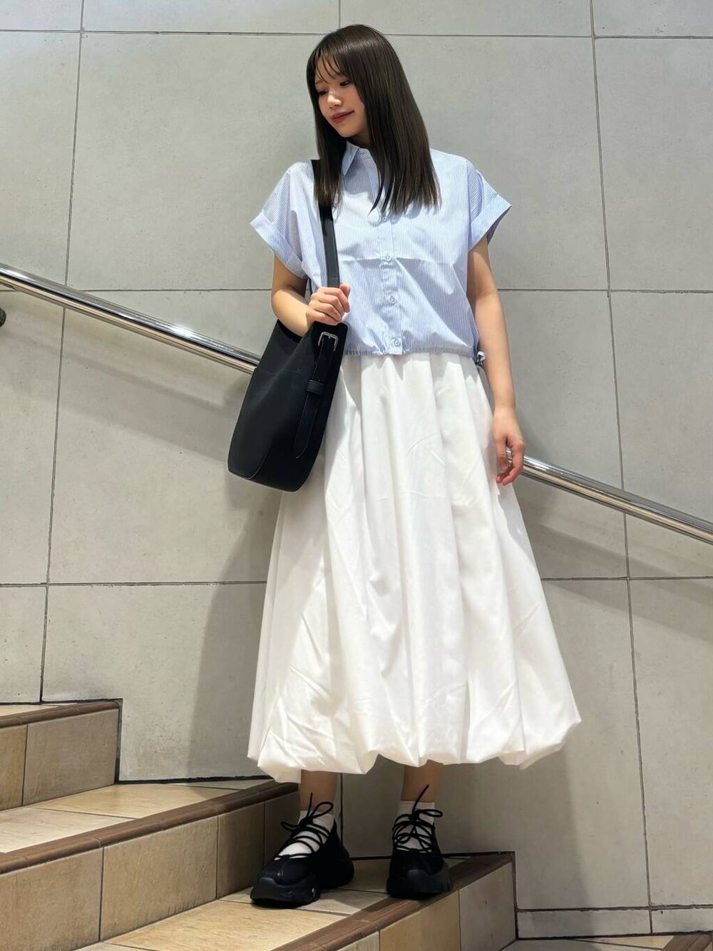 ブラック系のスニーカー、ホワイト系のスカート、ブラック系のショルダーバッグを着用したレディースの春コーディネートの3枚目の写真