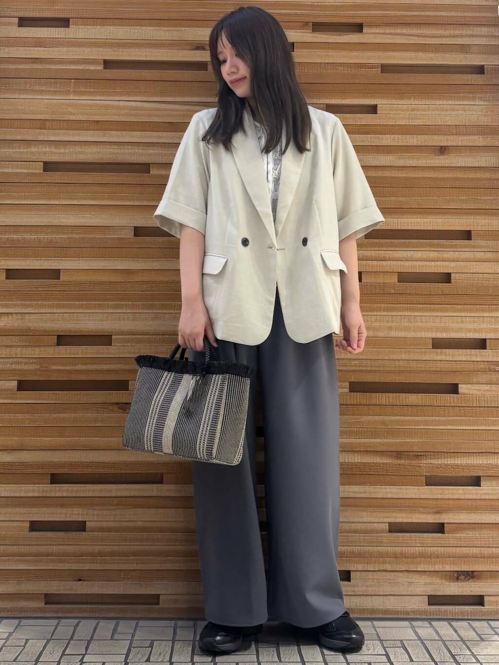 ブラック系のスニーカー、ベージュ系のその他アウター、ブラック系のショルダーバッグを着用したレディースの夏コーディネートの2枚目の写真