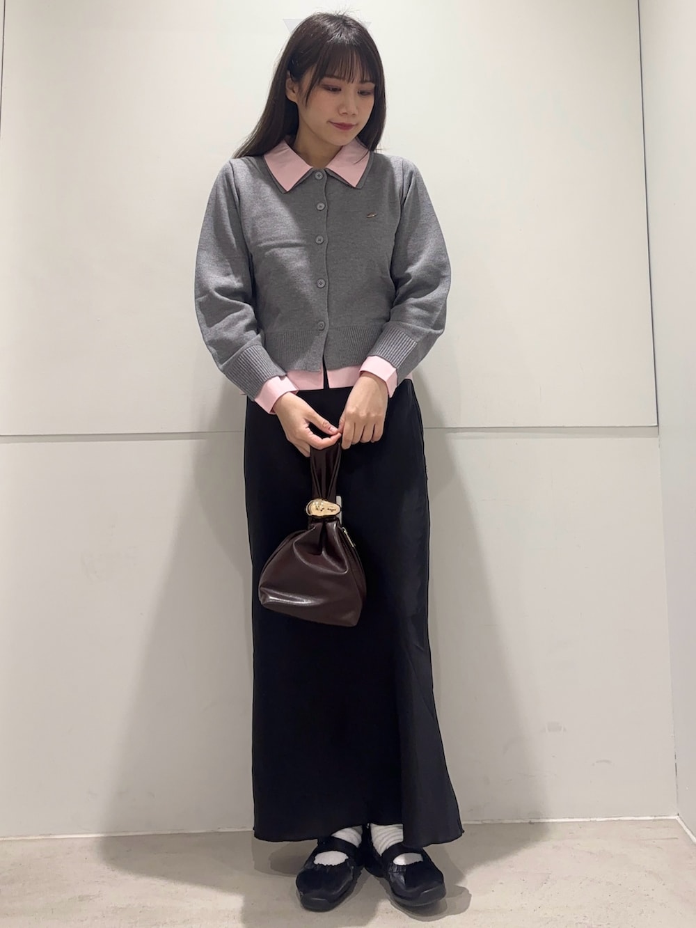 グレー系のカーディガン/ボレロ、ブラック系のスカート、ブラウン系のハンドバッグを着用したレディースの春コーディネートの2枚目の写真