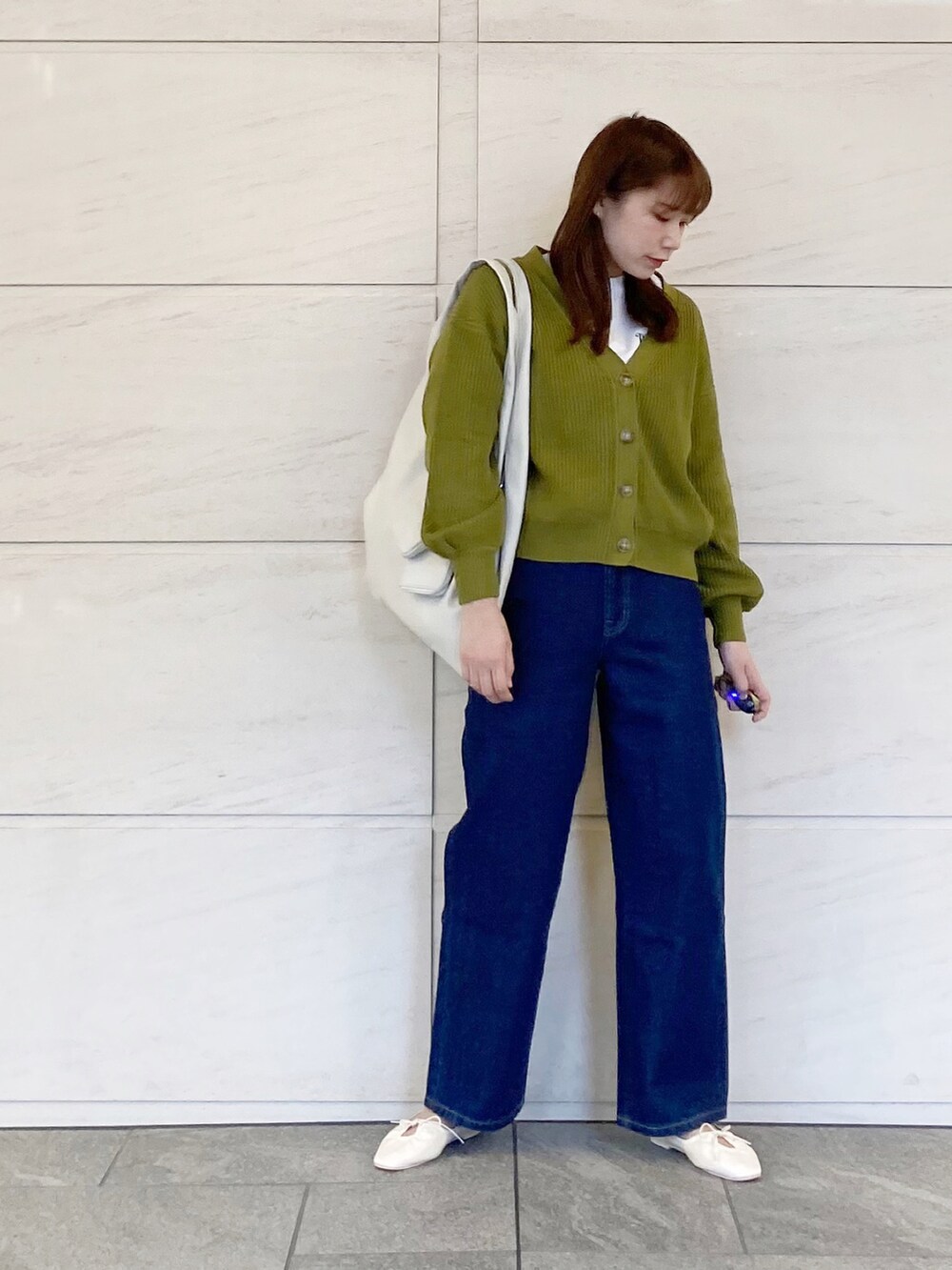 ブルー系のデニムパンツ、グリーン系のカーディガン/ボレロ、ホワイト系のショルダーバッグを着用したレディースの春コーディネートの2枚目の写真