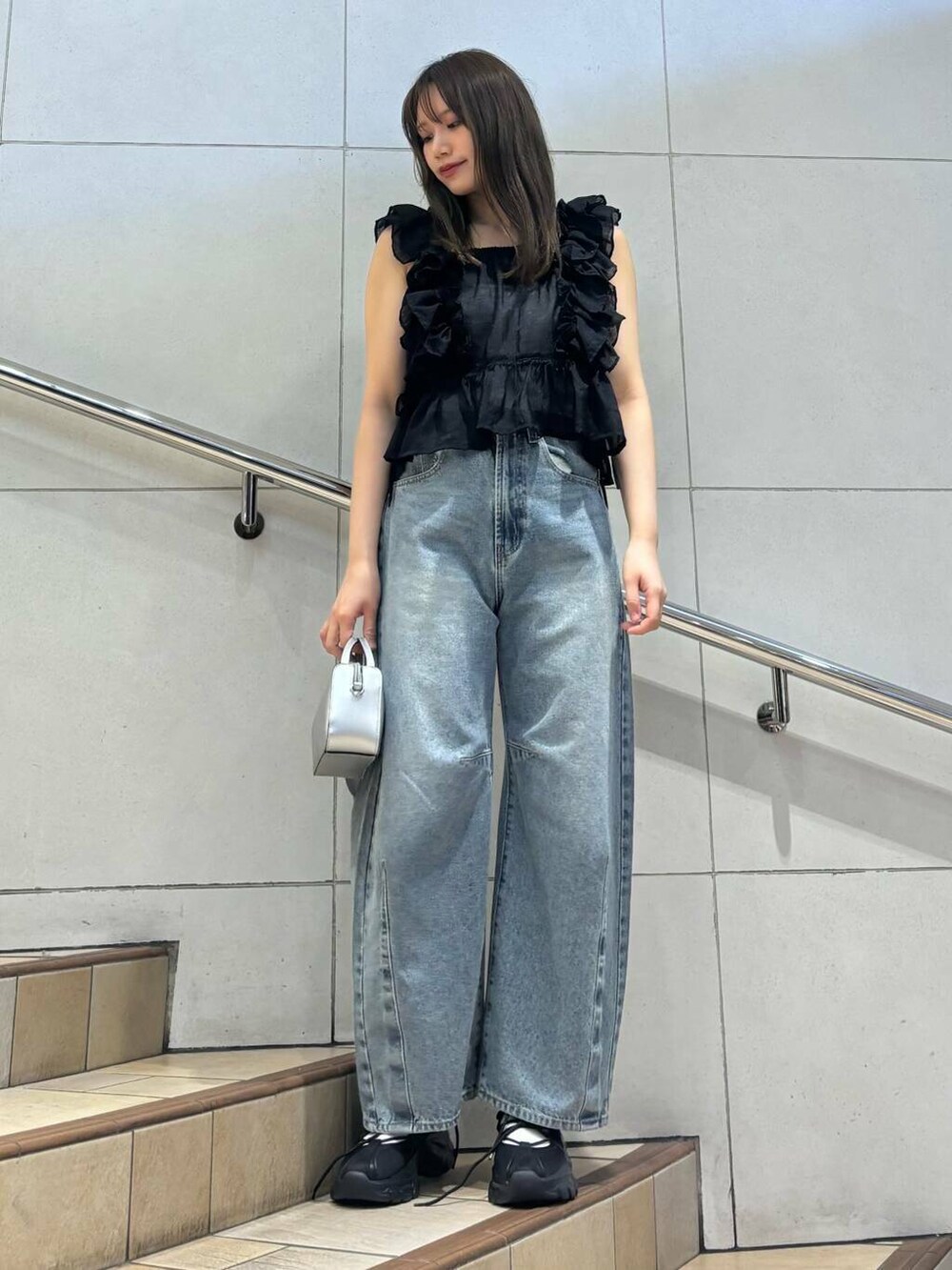 ブラック系のスニーカー、ホワイト系のキャミソール、ブルー系のデニムパンツを着用したレディースの春コーディネートの5枚目の写真