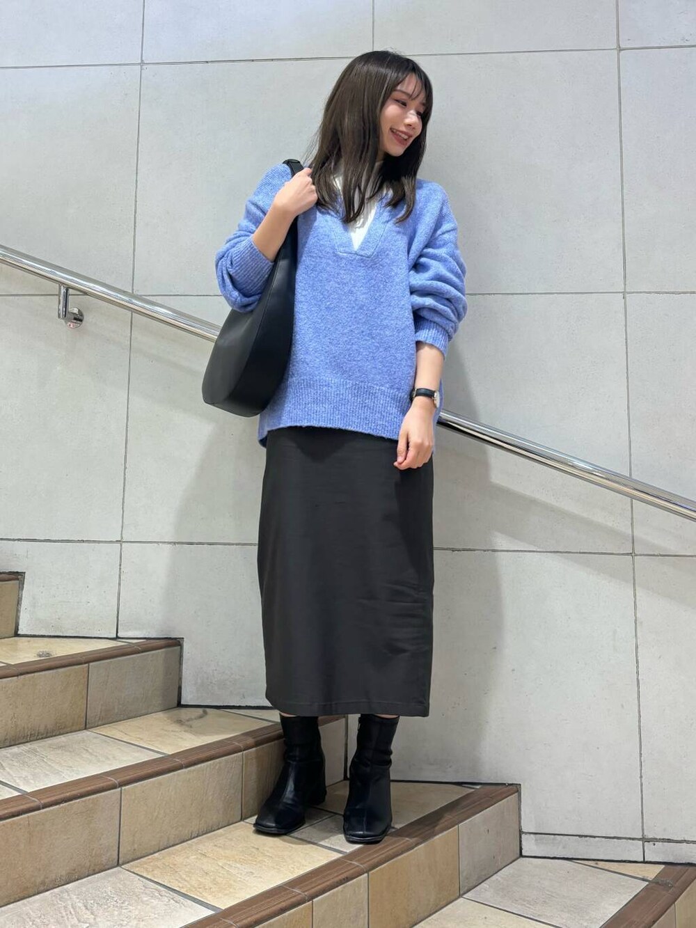 ブラック系のブーツ、グレー系のスカート、ブルー系のニット/セーターを着用したレディースの冬コーディネートの3枚目の写真