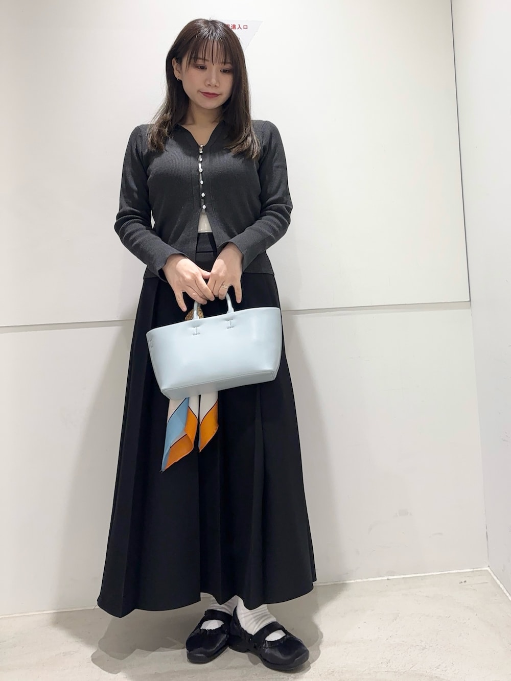グレー系のカーディガン/ボレロ、ブラック系のスカート、ブルー系のトートバッグを着用したレディースの春コーディネートの2枚目の写真