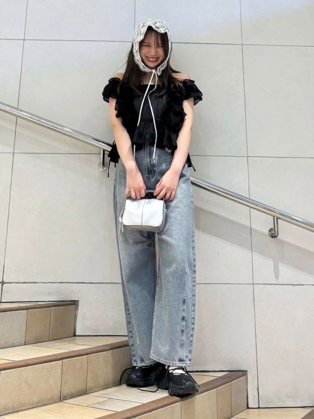 ブラック系のスニーカー、ホワイト系のキャミソール、ブルー系のデニムパンツを着用したレディースの春コーディネートの2枚目の写真