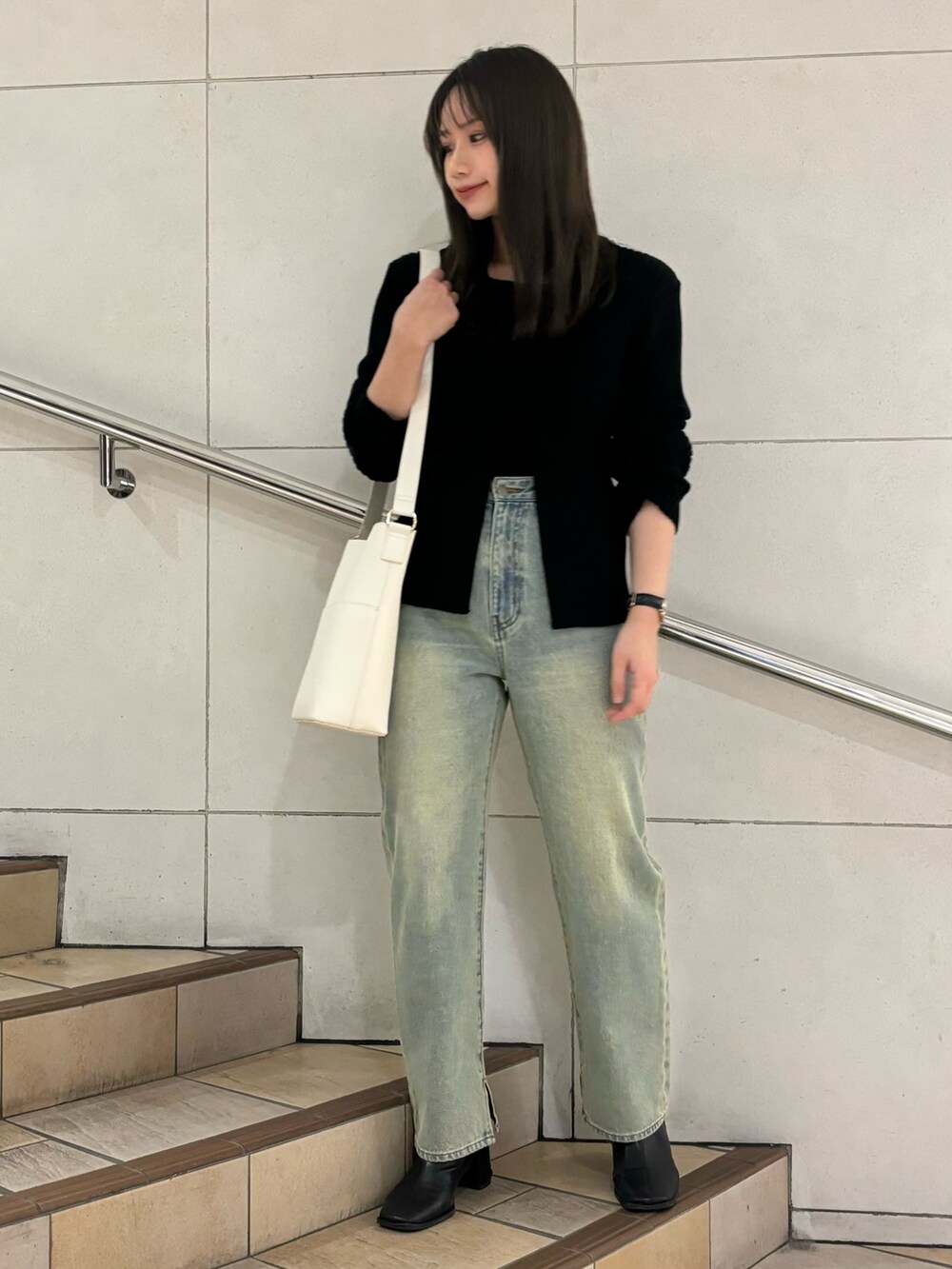 ベージュ系のショルダーバッグ、ブルー系のデニムパンツ、ブラック系のニット/セーターを着用したレディースの冬コーディネートの3枚目の写真
