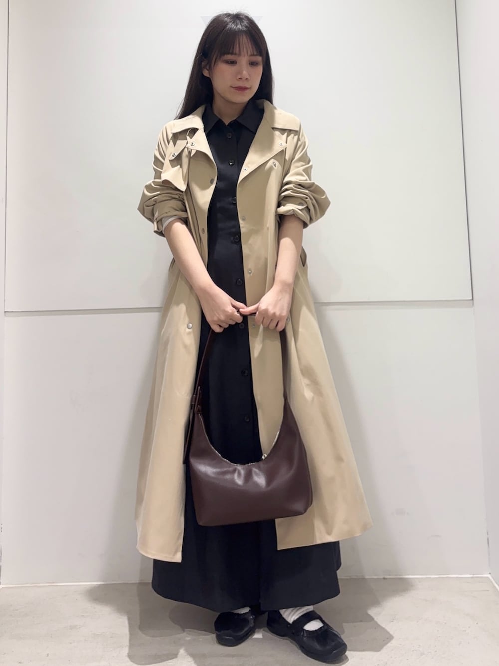 ベージュ系のトレンチコート、グレー系のワンピース、ブラウン系のハンドバッグを着用したレディースの春コーディネートの2枚目の写真