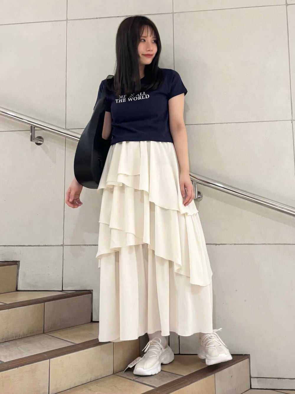 ブラック系のショルダーバッグ、ホワイト系のスカート、ホワイト系のスニーカーを着用したレディースの春コーディネートの3枚目の写真